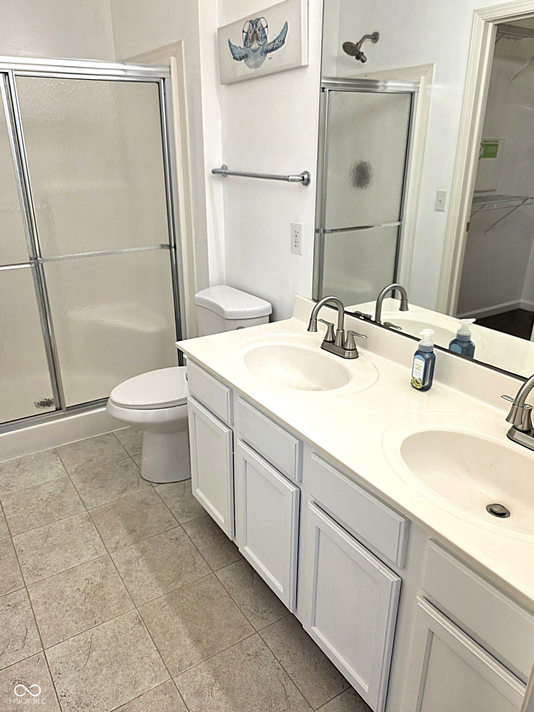 White double vanity with integrated sinks and brushed nickel faucets, set against a full-width mirror