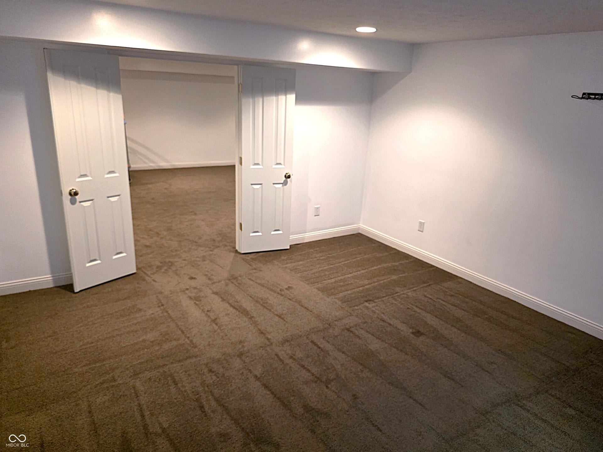 Recessed lighting, white walls, and neutral carpeting
