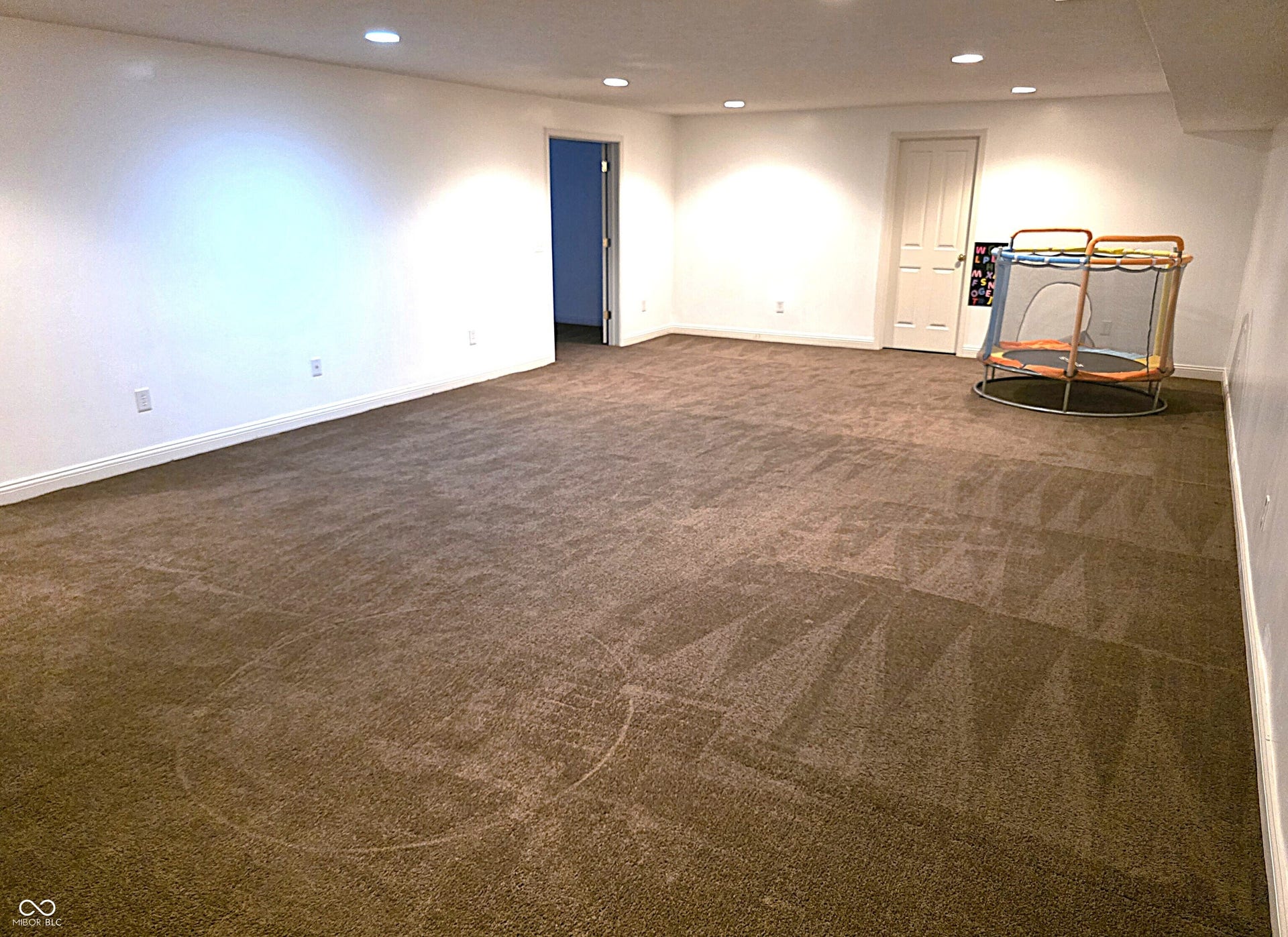 Expansive carpeted room featuring recessed lighting and white painted walls