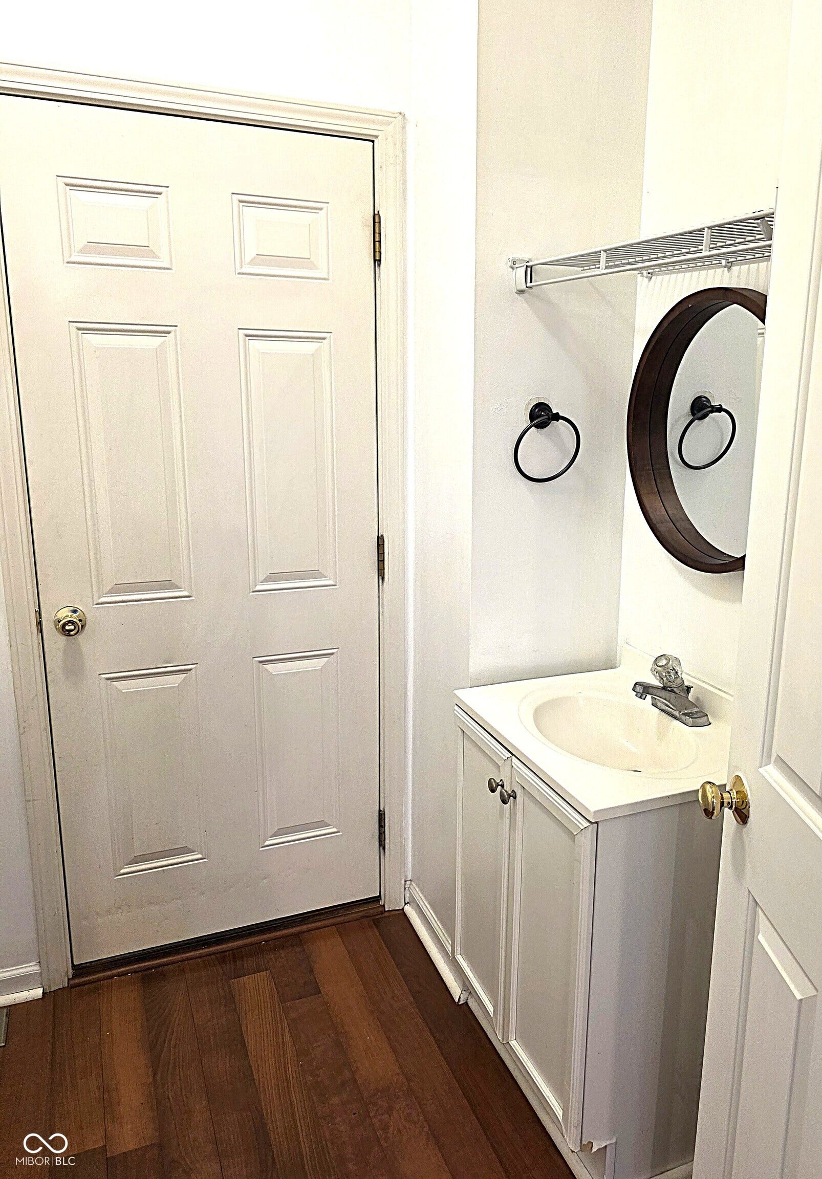 Wood-finish flooring with white paneled door with vanity sink