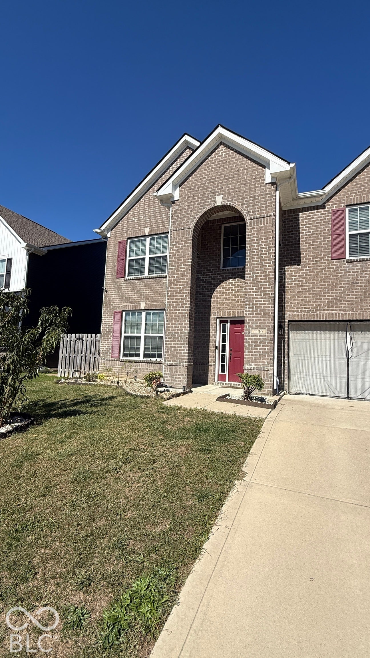 Brick exterior with red shutters, an arched entry, and an attached garage