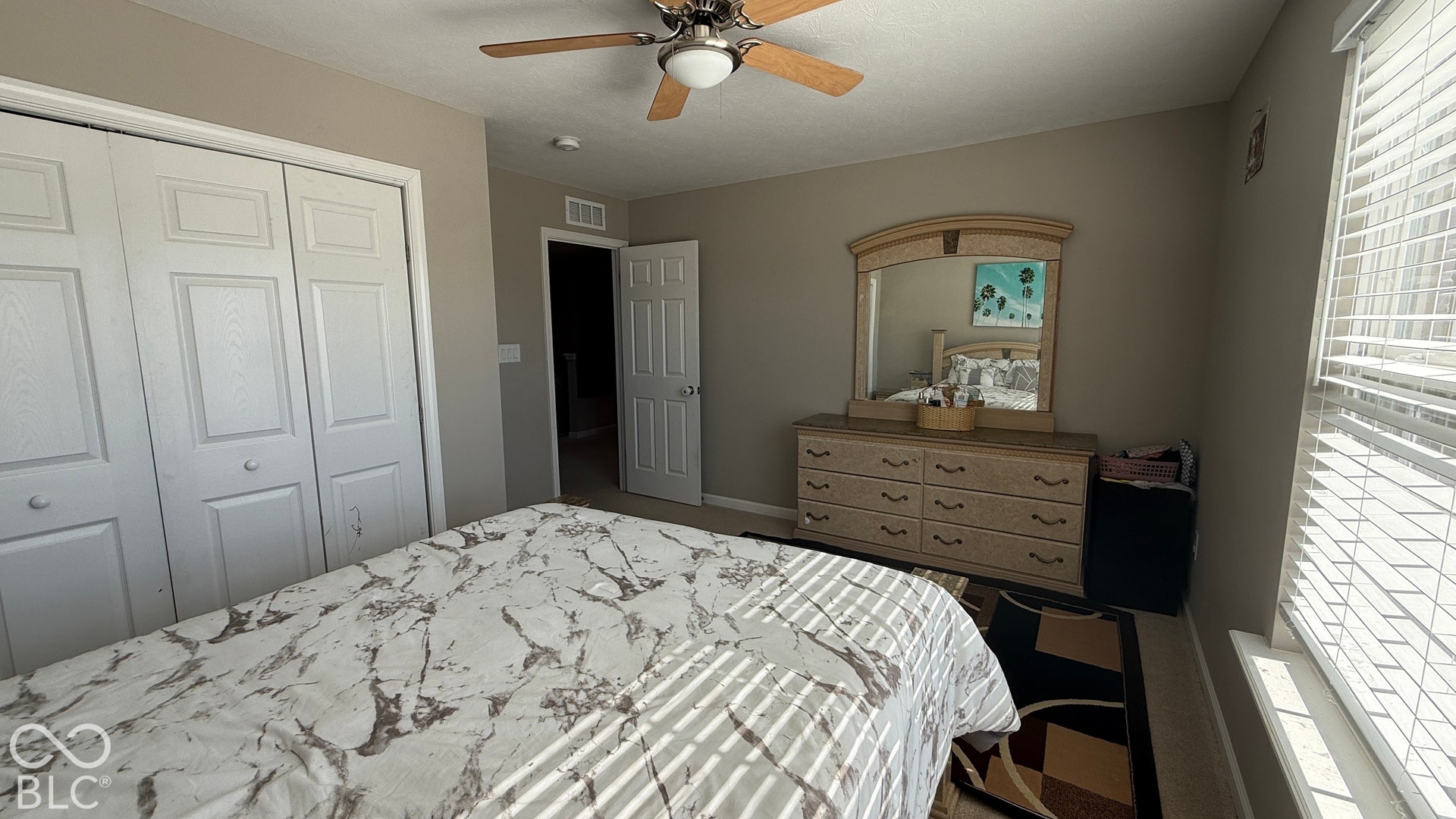 Built-in bi-fold closet doors, ceiling fan with integrated lighting, and window with horizontal blinds