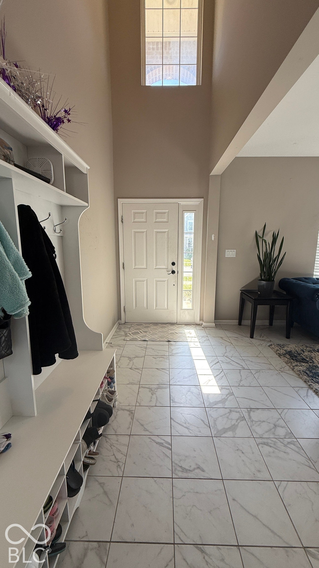 Two-story entryway with a large window and ceramic tile flooring