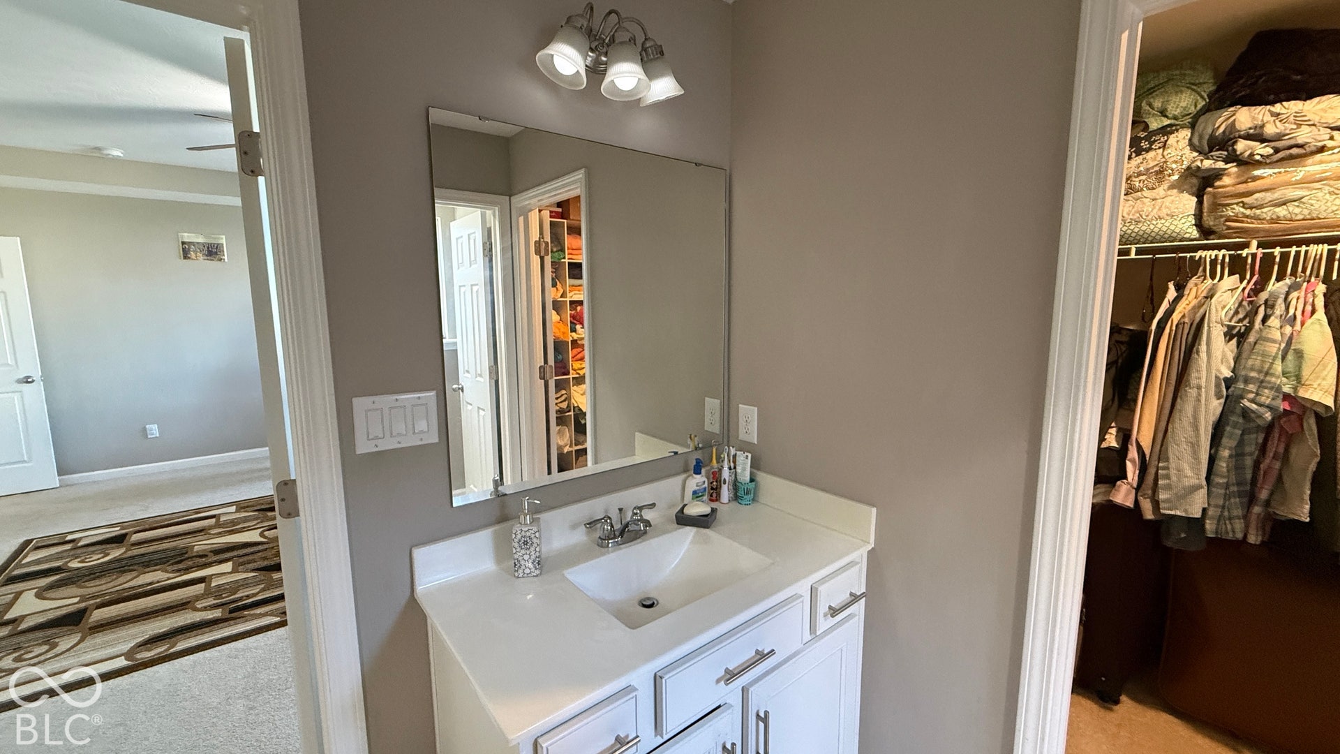 White vanity with an integrated sink, polished chrome faucet, and mirrored medicine cabinet