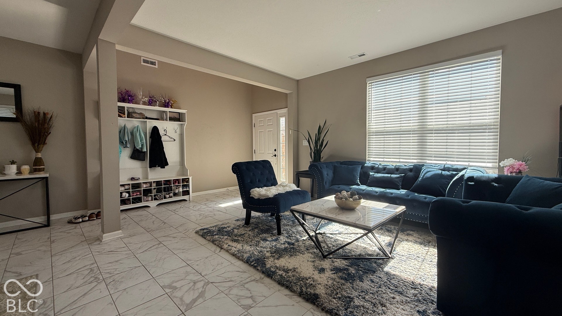 Tiled flooring, built-in mudroom storage, and a large window with blinds