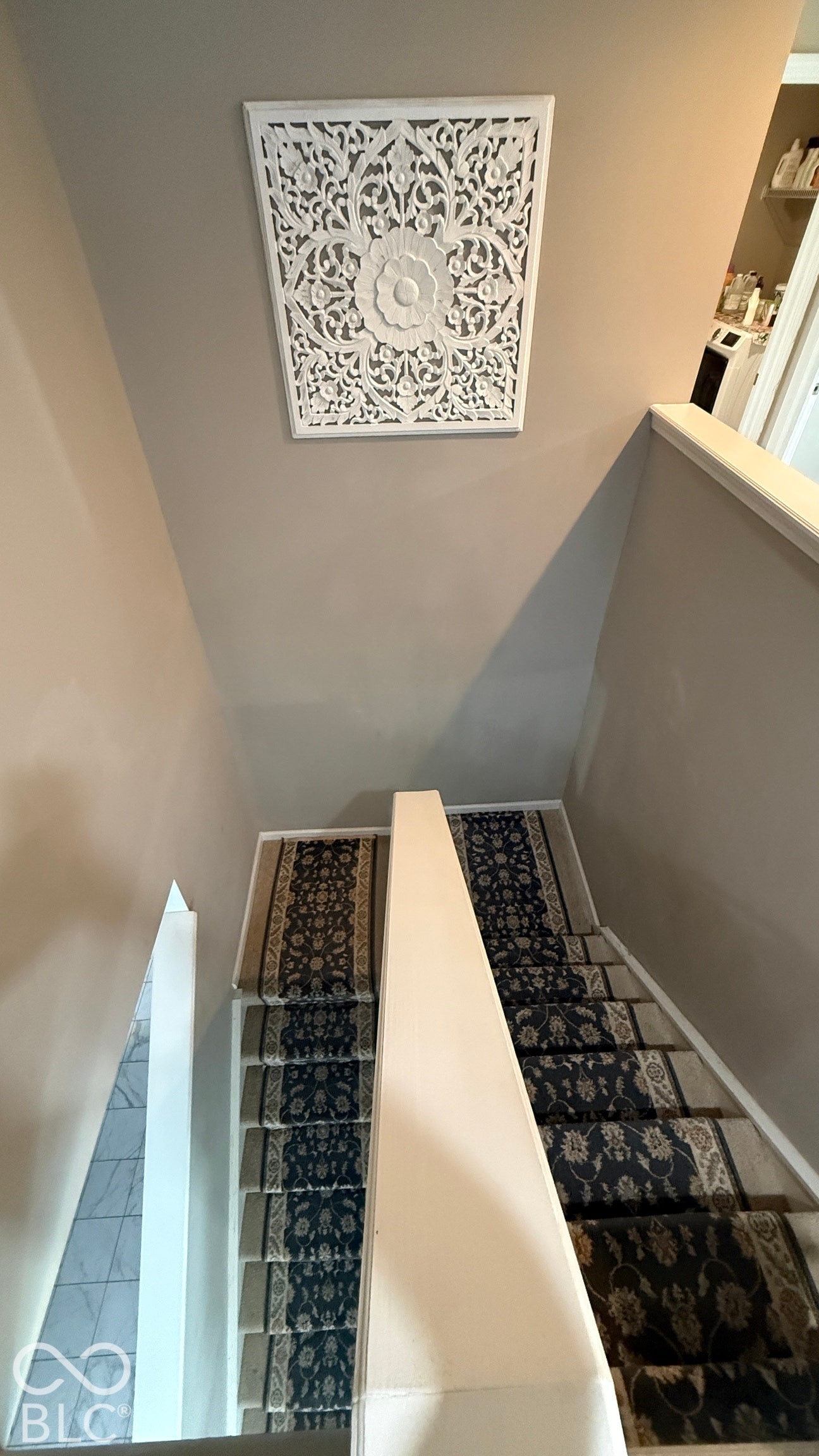 Staircase with patterned runner and light-toned wall