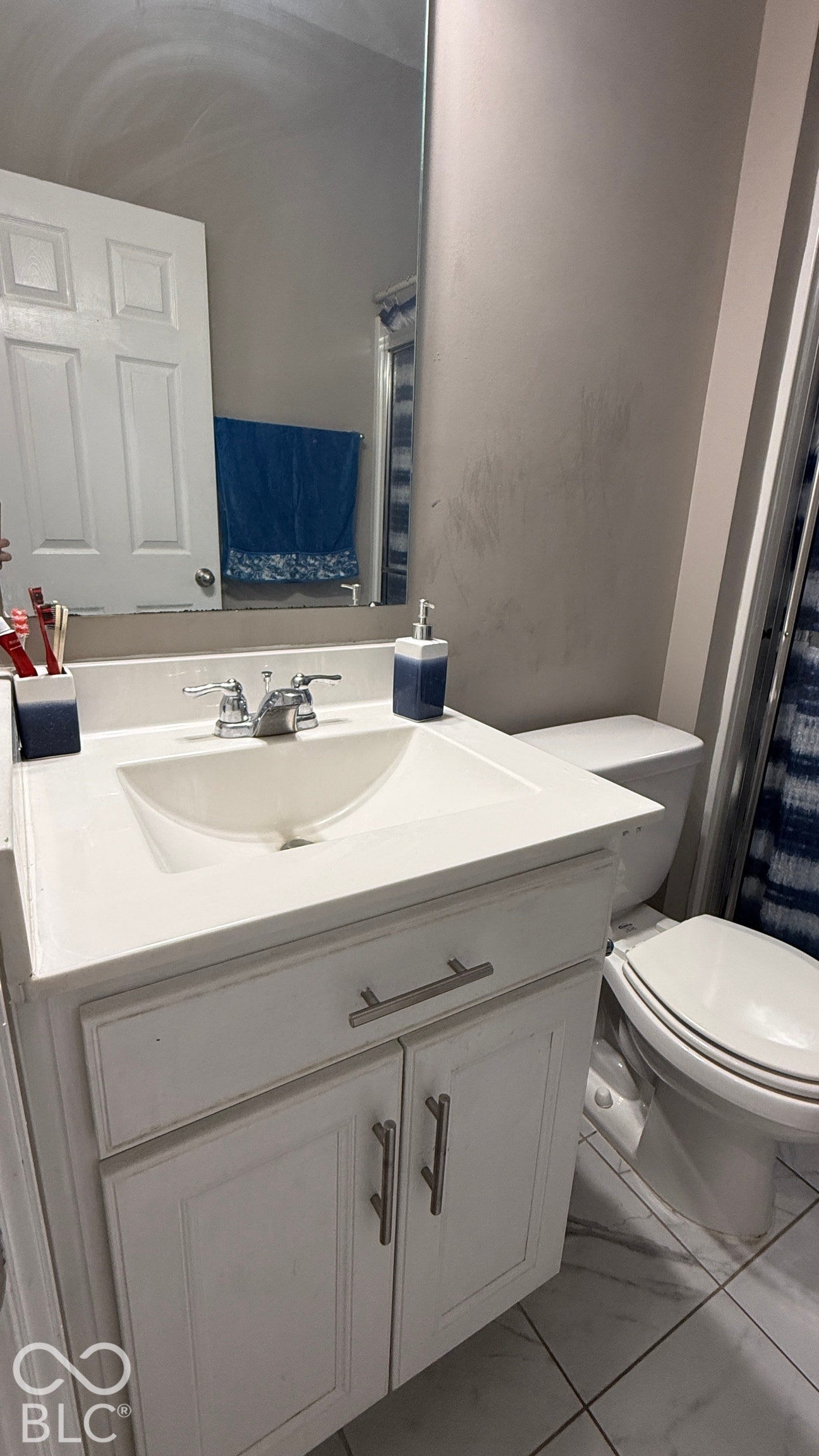 White vanity with panel-front cabinetry, integrated sink, and brushed nickel hardware