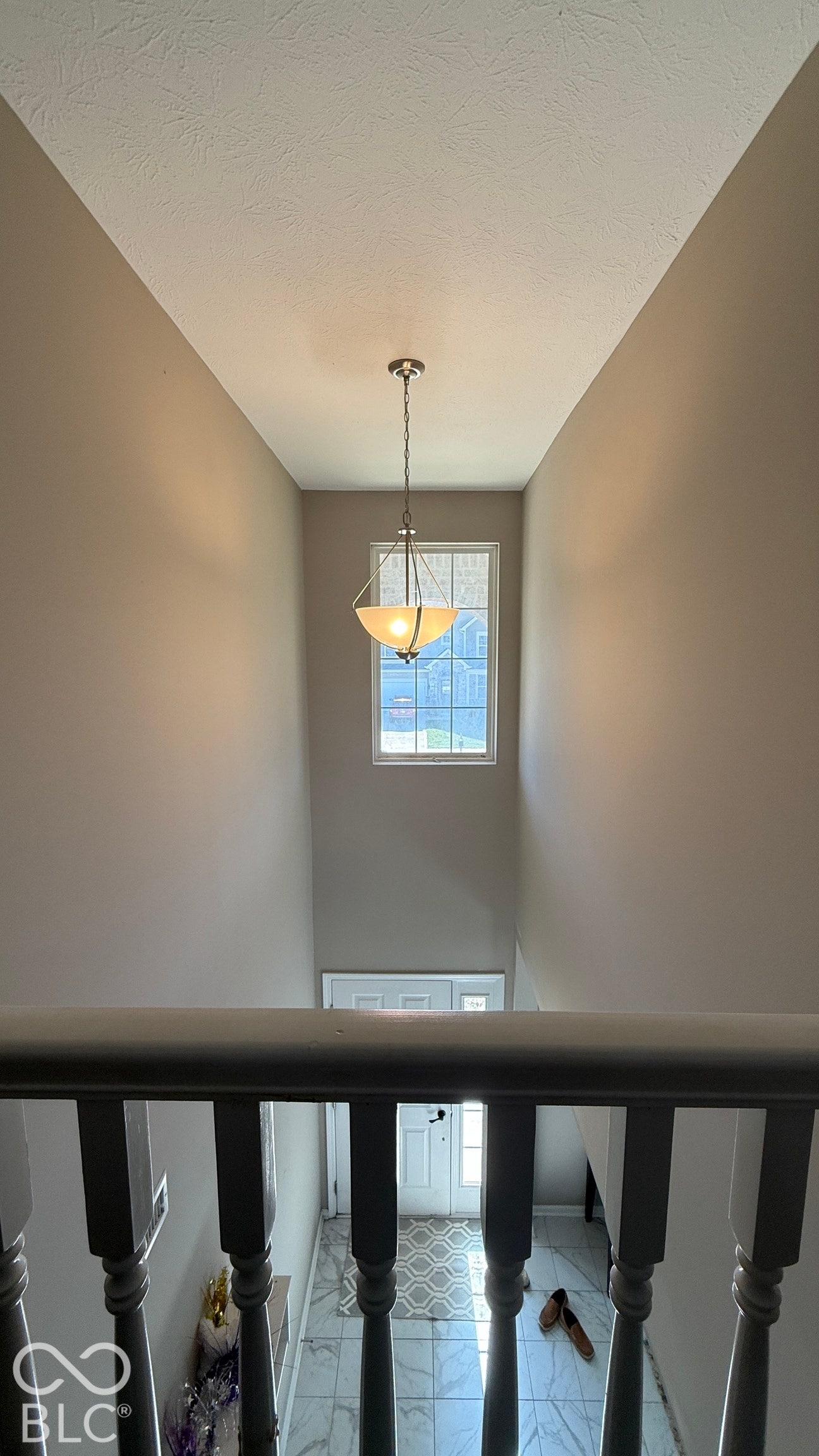 Two-story entryway with a decorative chandelier, transom window, and tiled flooring