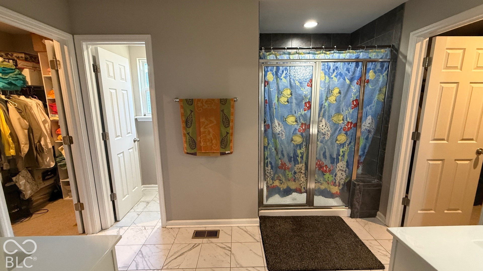 Tiled flooring with a large walk-in shower enclosure, recessed lighting, and a built-in closet with shelving
