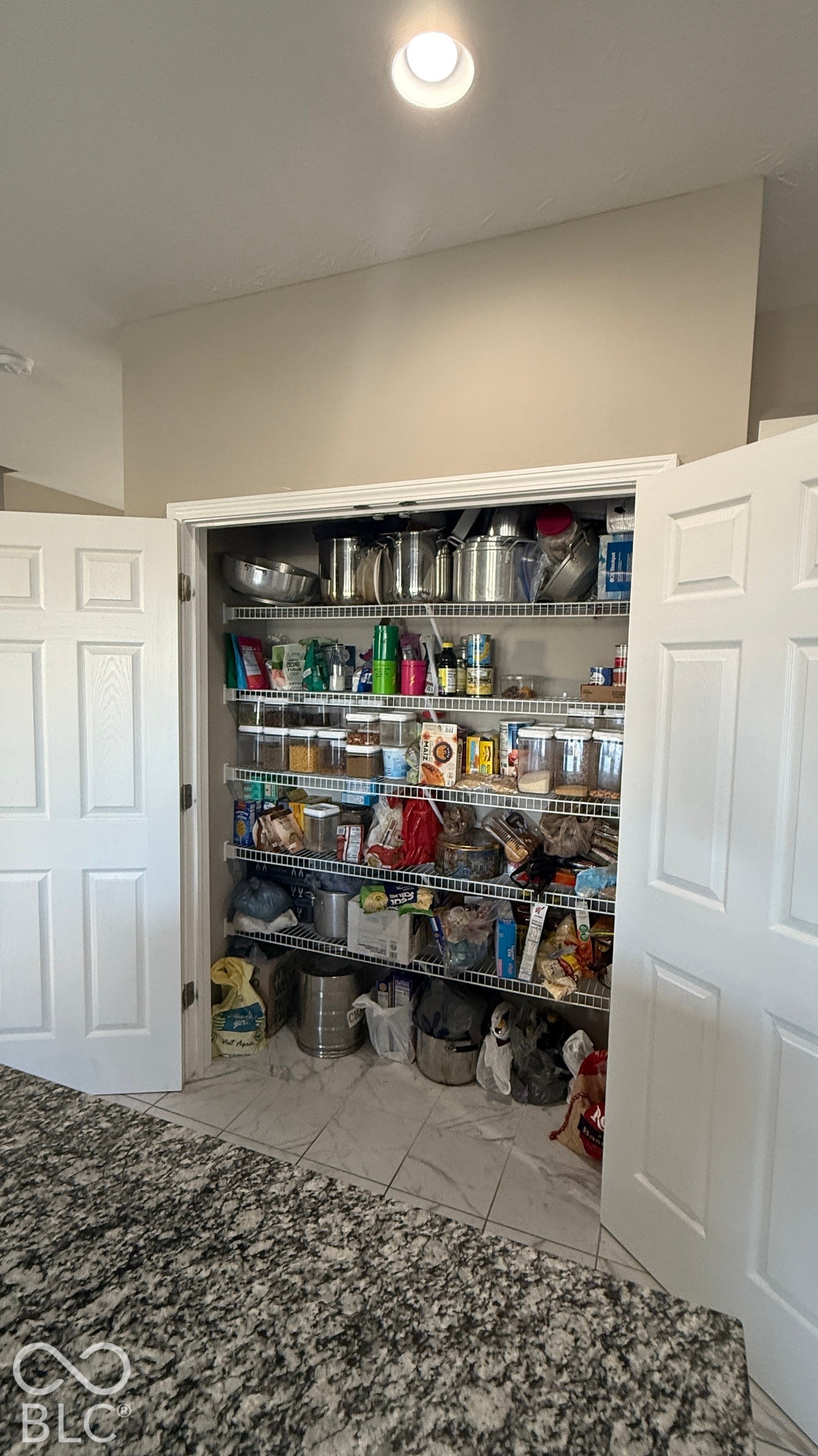 Pantry with double panel doors, wire shelving, recessed lighting, and tile flooring