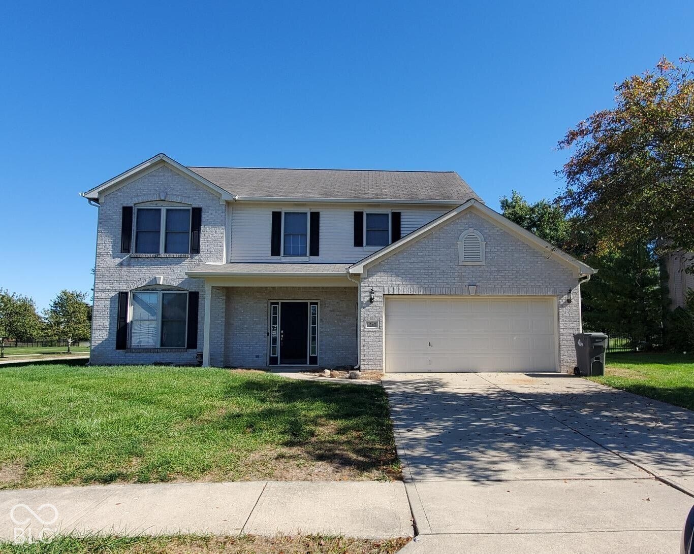 Two-story residence featuring a brick and siding exterior, an attached two-car garage, and a covered front entry