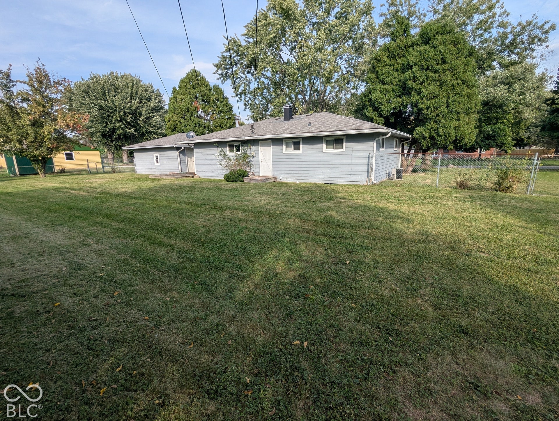 364 Robbins Drive, Greenwood, IN 46142 Exterior featuring horizontal siding, a hipped roof, concrete patio, chain-link perimeter fencing, and mature trees