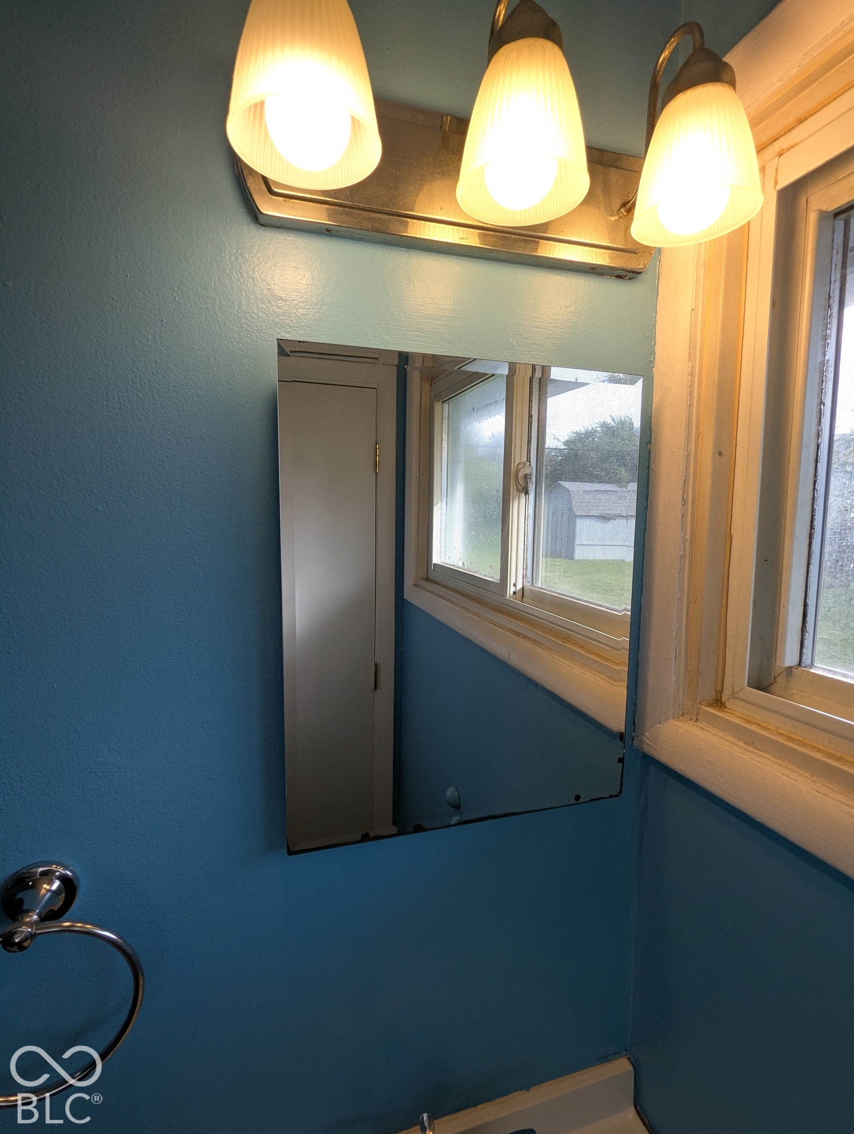 364 Robbins Drive, Greenwood, IN 46142 Wall-mounted light fixture with three sconces, bright blue wall finish, and a rectangular mirror