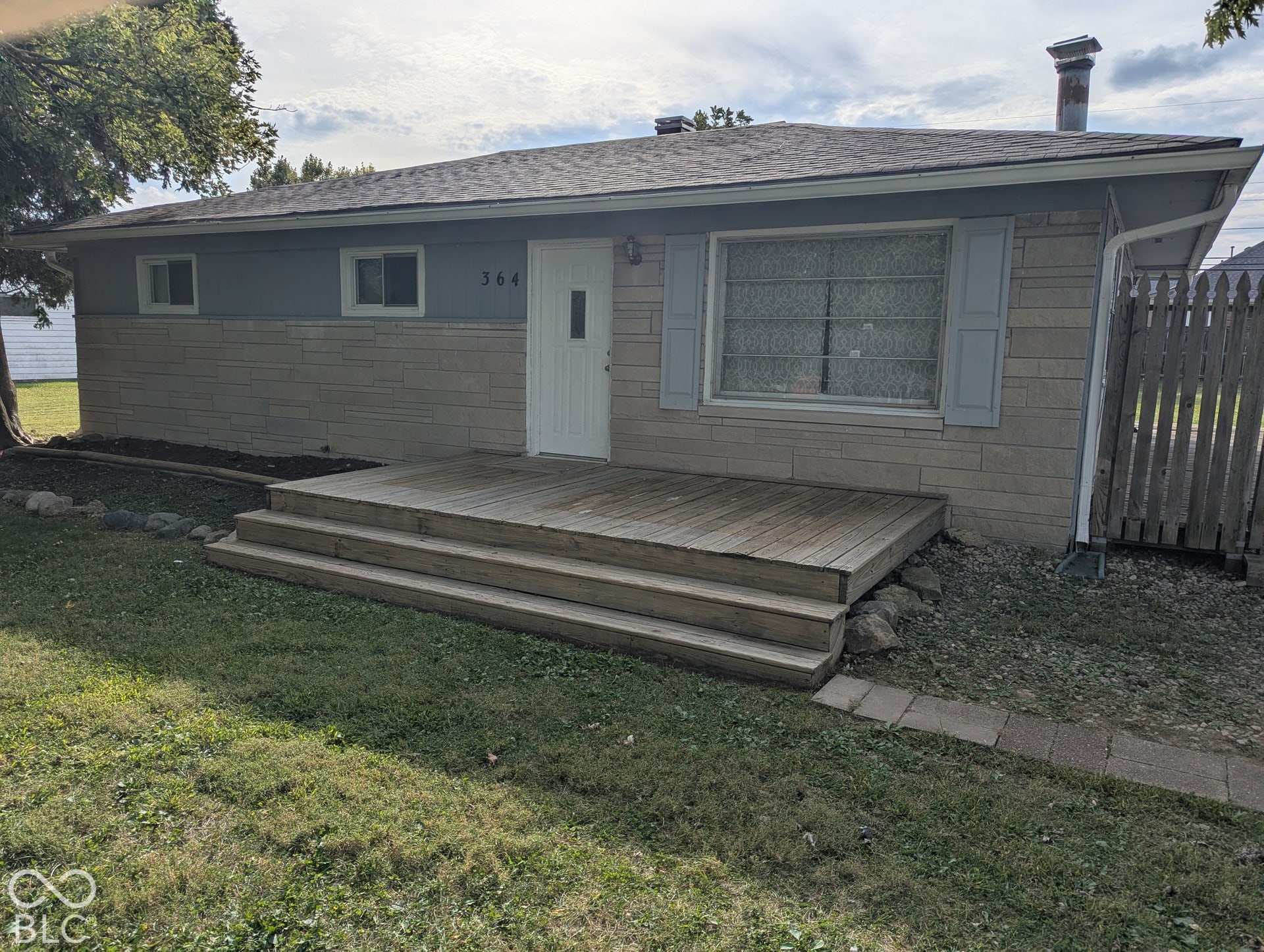 364 Robbins Drive, Greenwood, IN 46142 Single-story exterior with a wood deck entry, limestone and wood siding, and a gray shingle roof