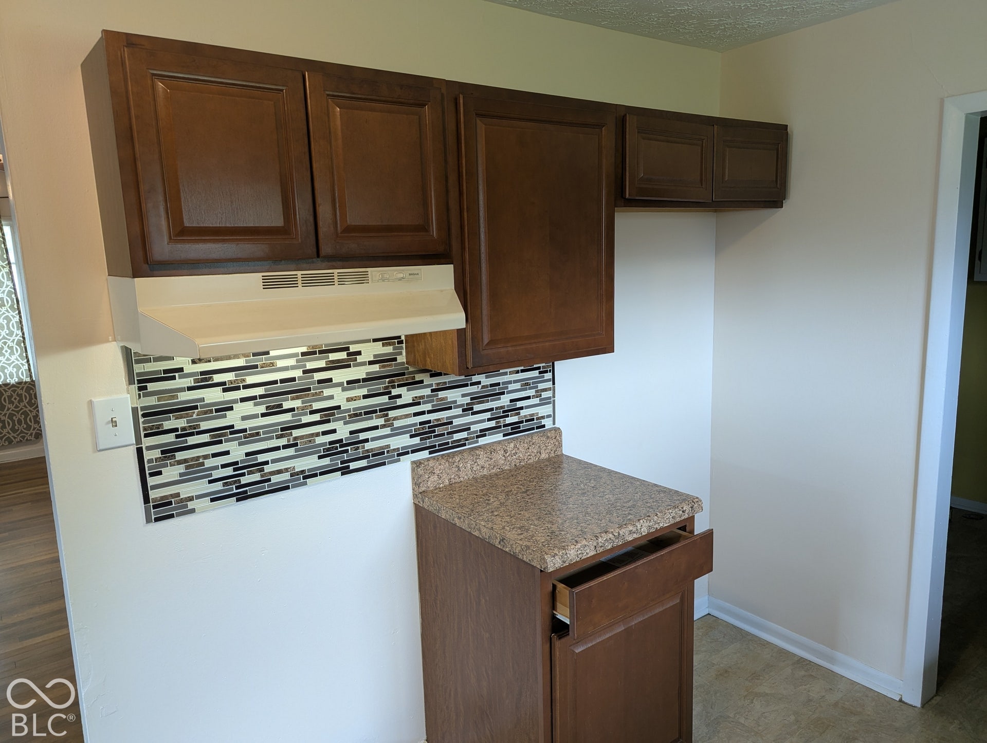 364 Robbins Drive, Greenwood, IN 46142 Kitchen area featuring wood-finish cabinetry, laminate-surface countertop, and a multi-toned horizontal mosaic tile backsplash