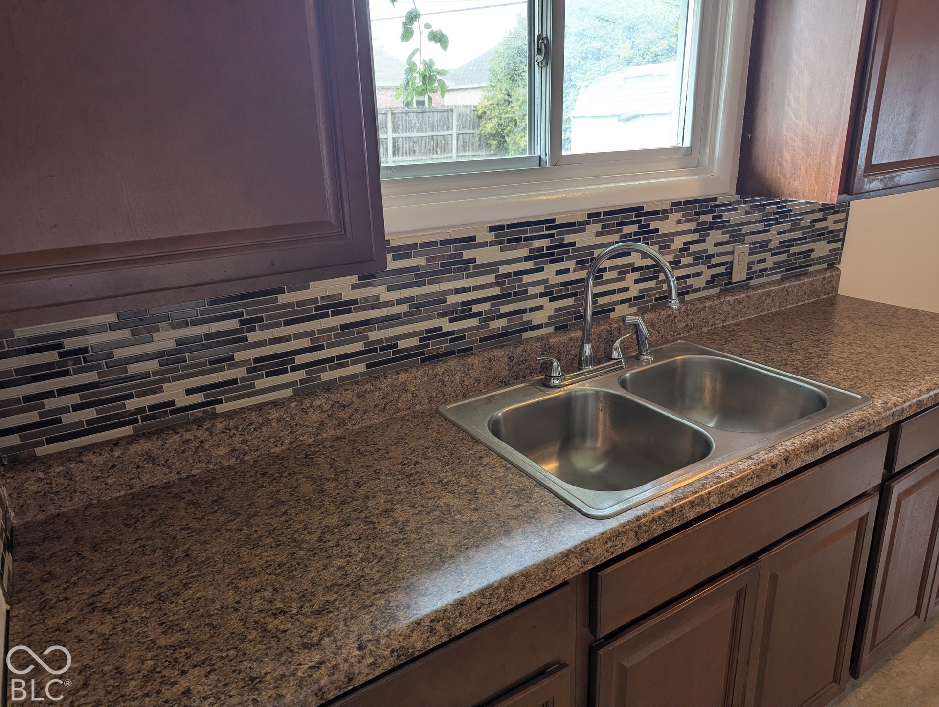 364 Robbins Drive, Greenwood, IN 46142 Kitchen featuring dark wood-finish cabinetry, a multicolored mosaic tile backsplash, a double-basin stainless steel sink, and a high-arc chrome faucet