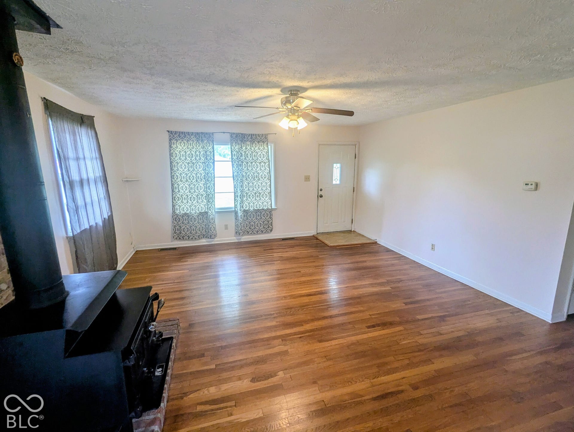 364 Robbins Drive, Greenwood, IN 46142 Wood-finish flooring throughout, wood-burning stove with brick hearth, and ceiling-mounted light fixture with fan
