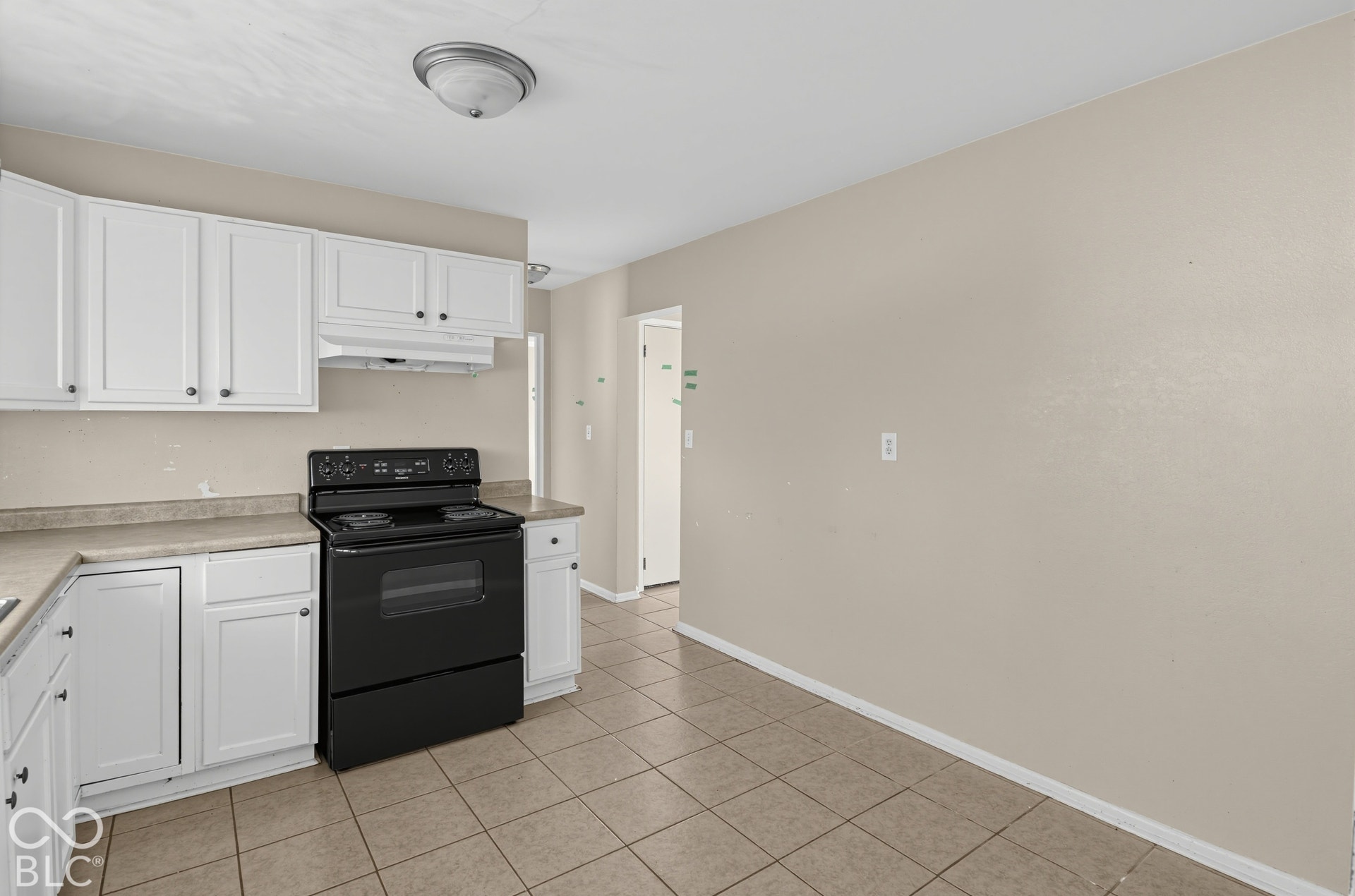 3733 Ireland Drive, Indianapolis, IN 46235 White cabinetry with dark hardware, black range, tile flooring, and neutral wall paint