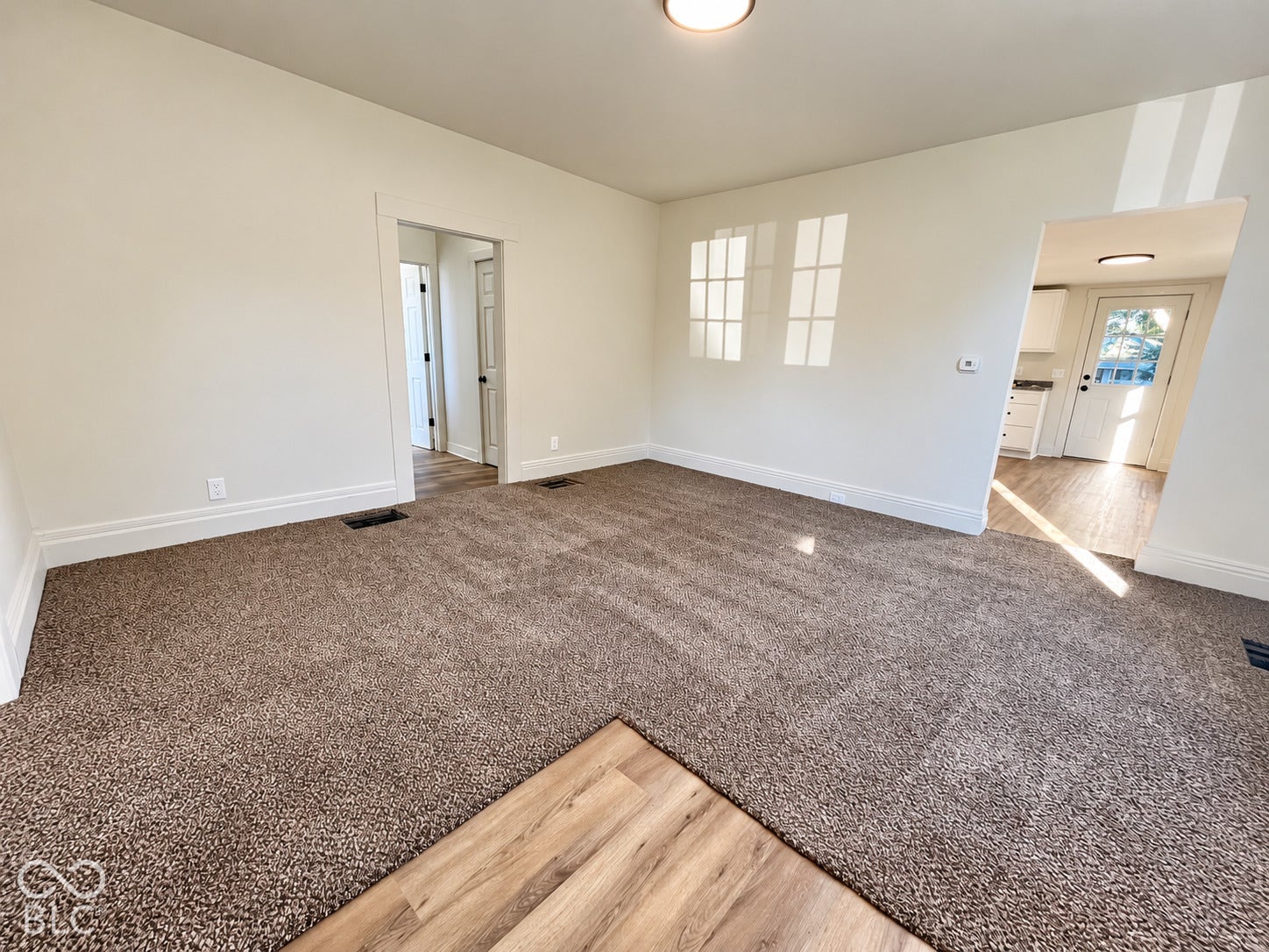 Recessed lighting, wood-finish flooring, and light-colored carpeting
