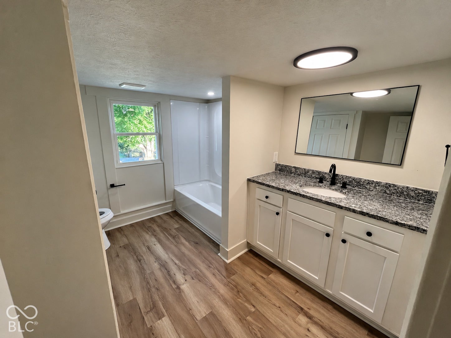 White vanity with granite countertop, undermount sink, and matte black faucet