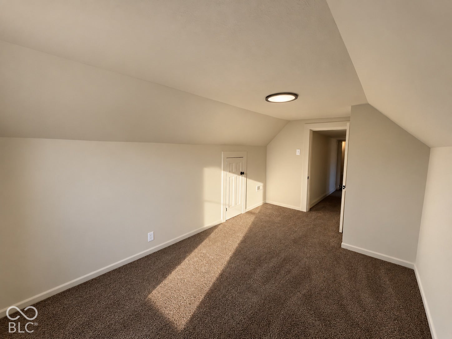 Carpeted room featuring a sloped ceiling and flush-mount lighting