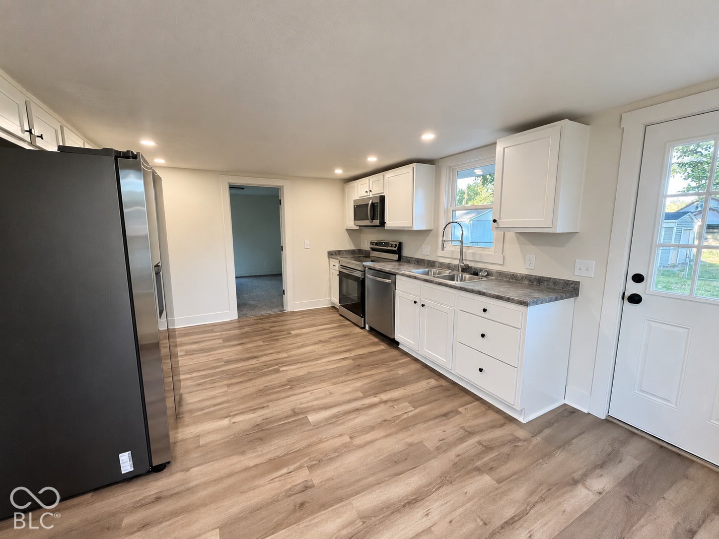 Kitchen featuring wood-finish flooring, white cabinetry, dark countertops, recessed lighting, and stainless steel appliances