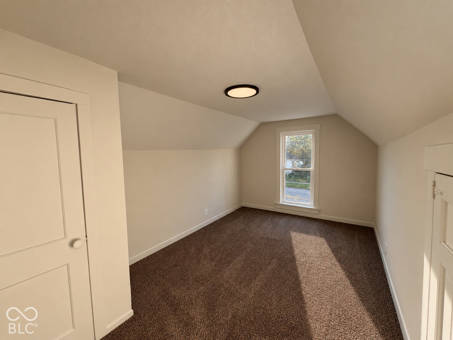 Sloped ceilings, neutral wall tones, and plush brown carpeting