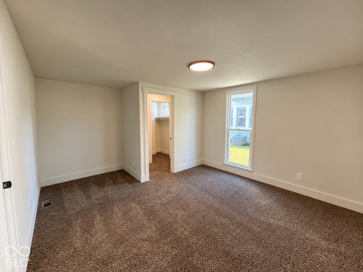 Neutral wall paint, brown carpeting, recessed window, and flush mount ceiling light fixture