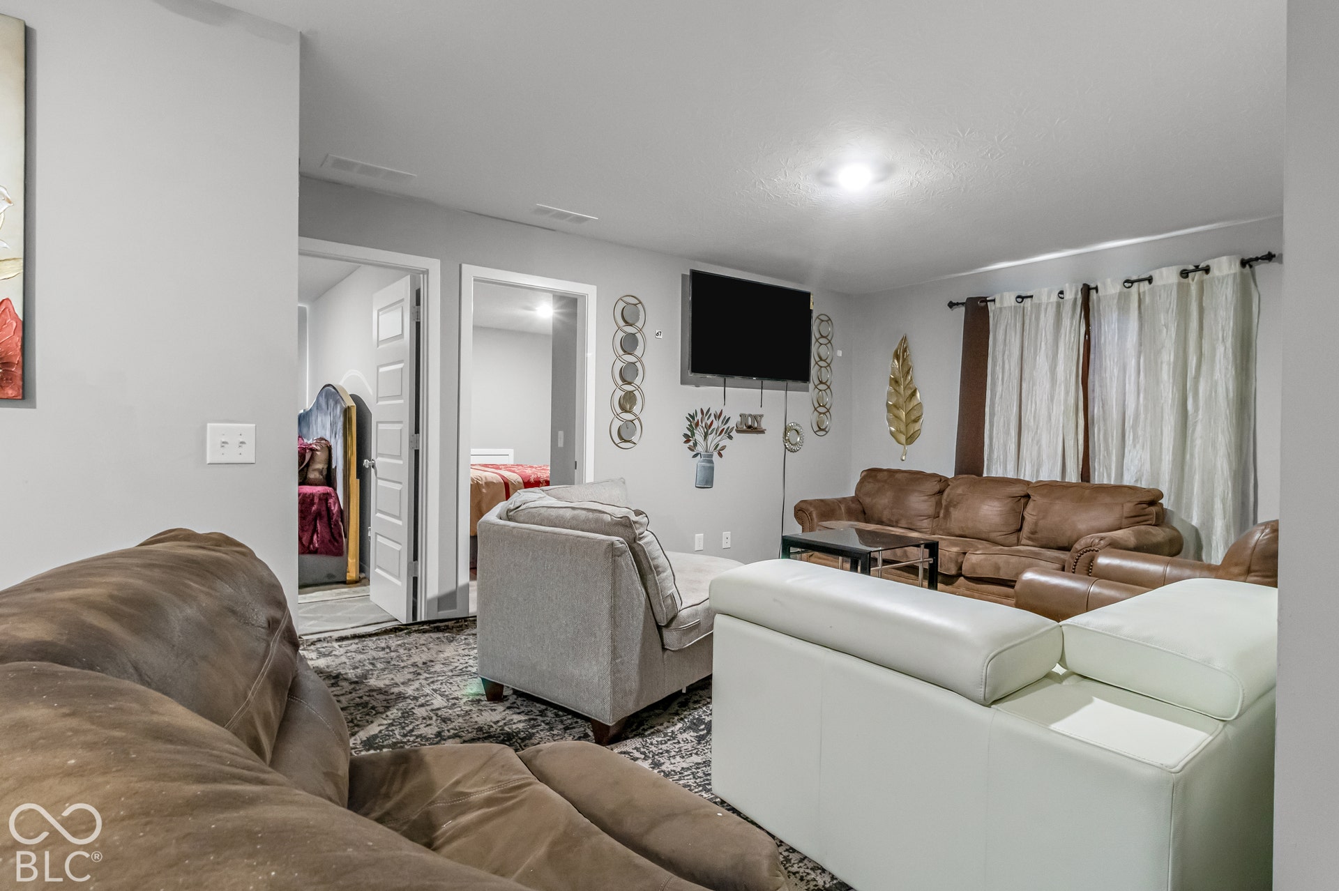 Two panel doors leading to additional rooms, a wall-mounted television, and flush-mount lighting