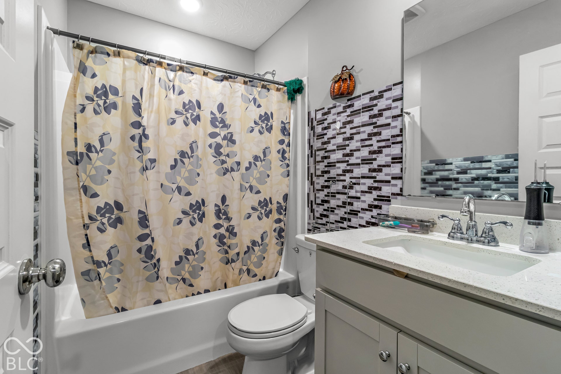 White vanity with a quartz-finish countertop and chrome faucet