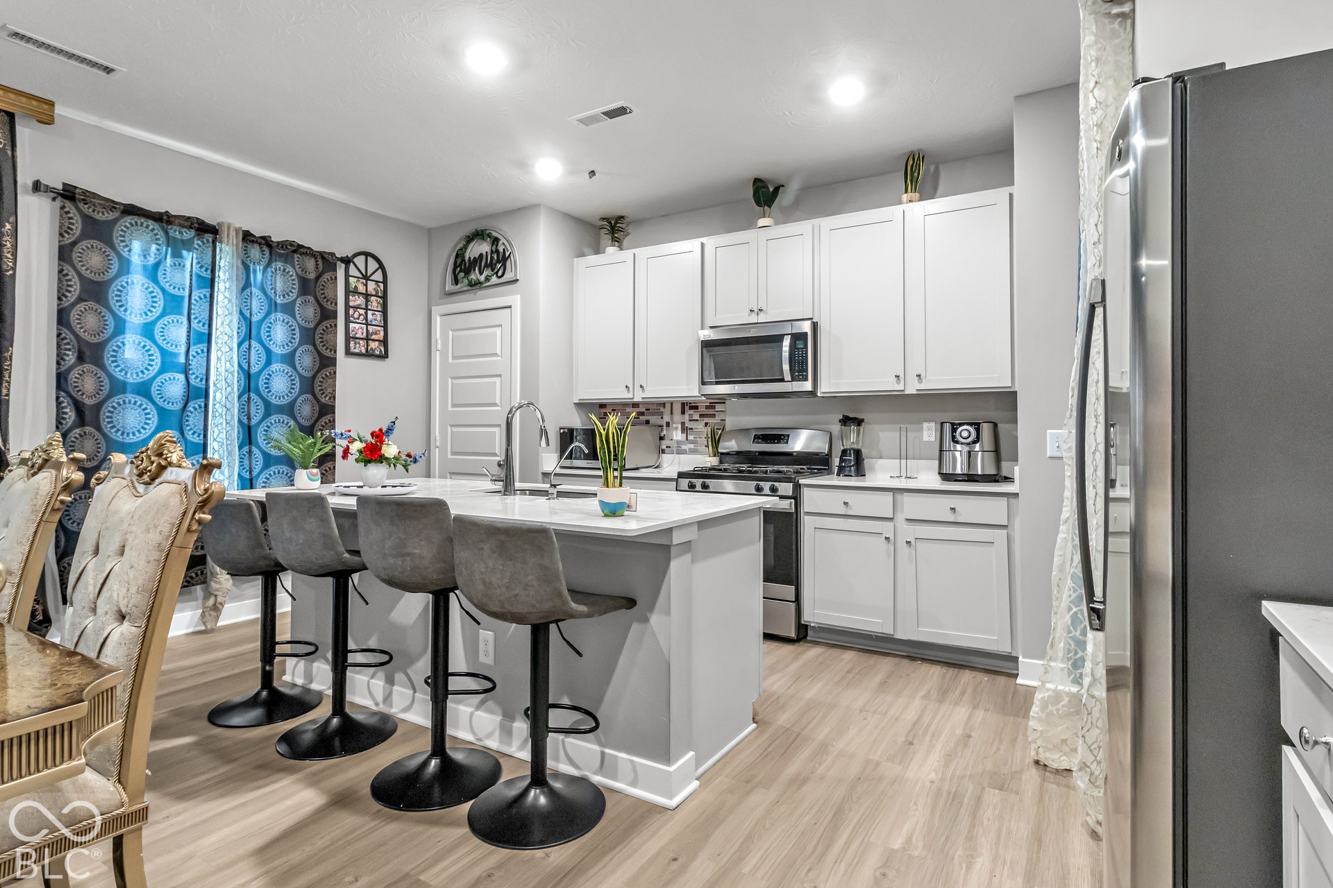 Modern kitchen featuring light cabinetry, stainless steel appliances, an island with countertop seating, and light wood-finish flooring