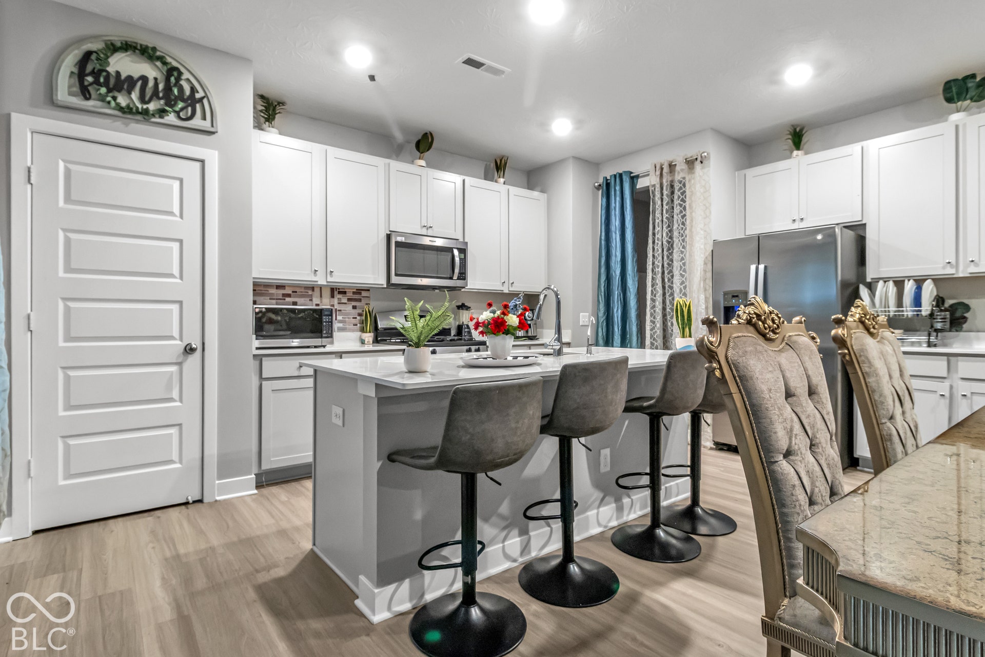 Kitchen featuring light wood-finish flooring, white cabinetry, stainless steel appliances, and a central island with countertop seating