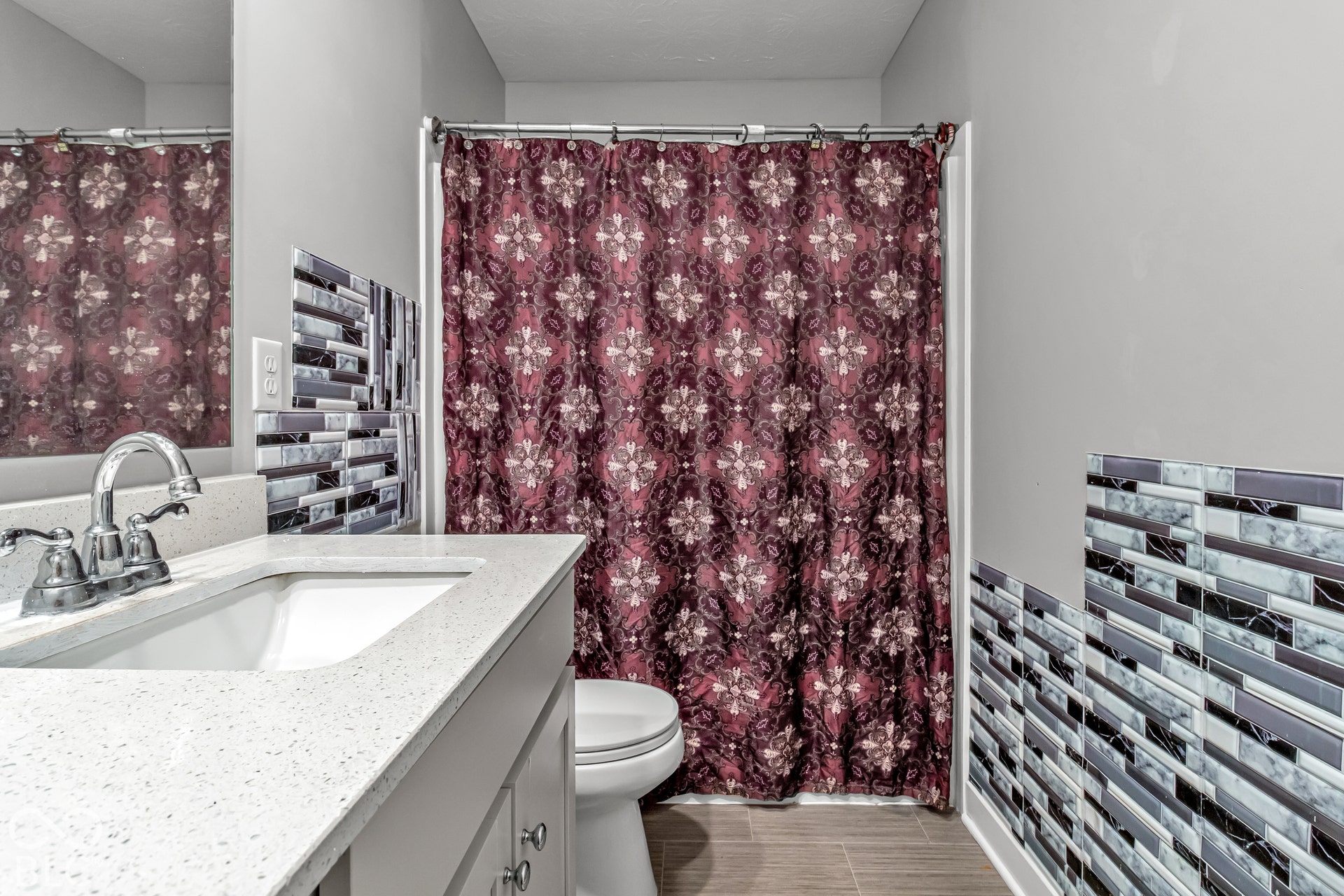 White vanity with integrated sink, chrome faucet, and mosaic tile backsplash