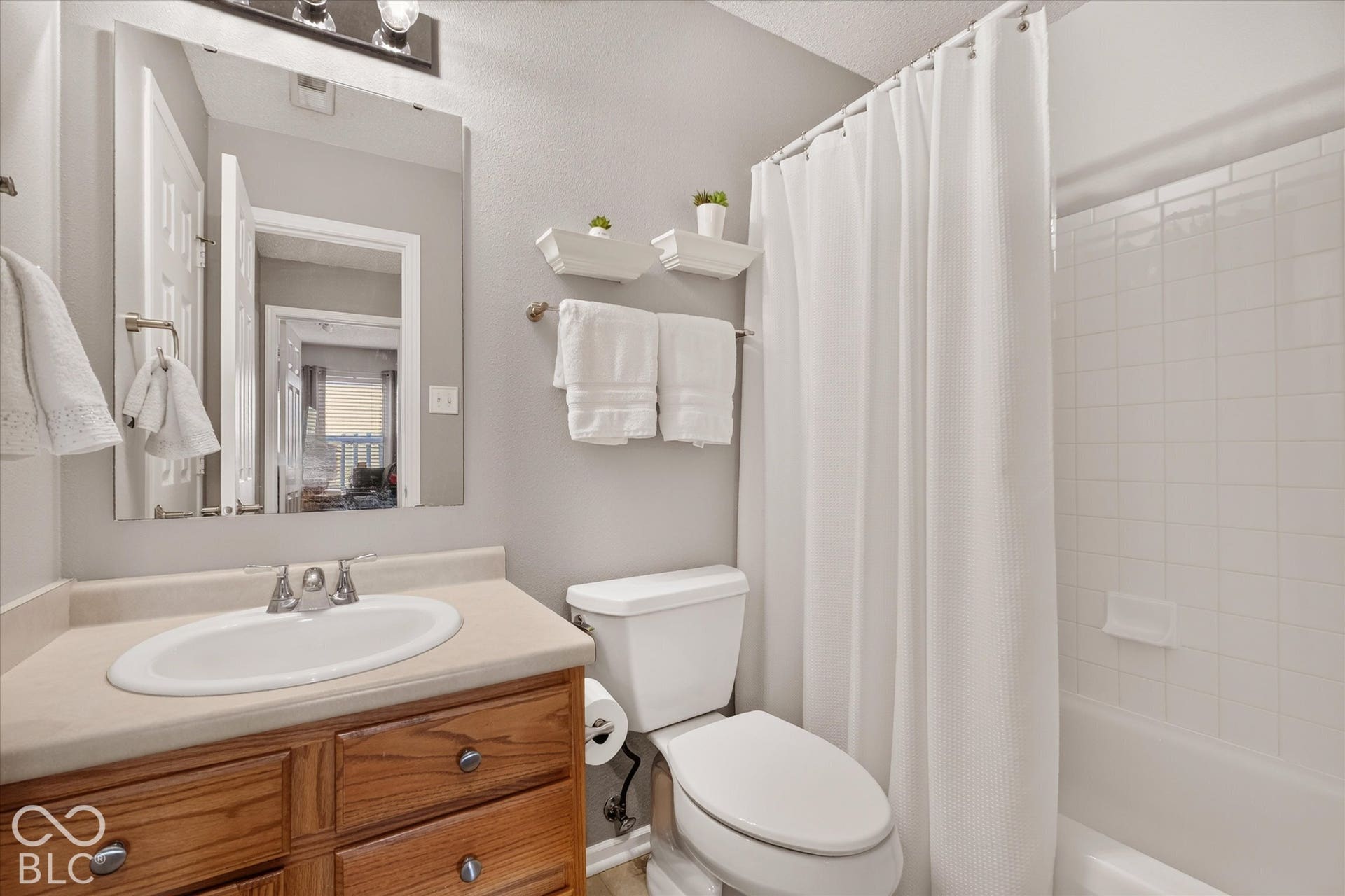 12980 Coyote Run, Fishers, IN 46038 Bathroom featuring a wood-finish vanity with a single basin, a framed mirror, and a full-size bathtub with subway tile surround