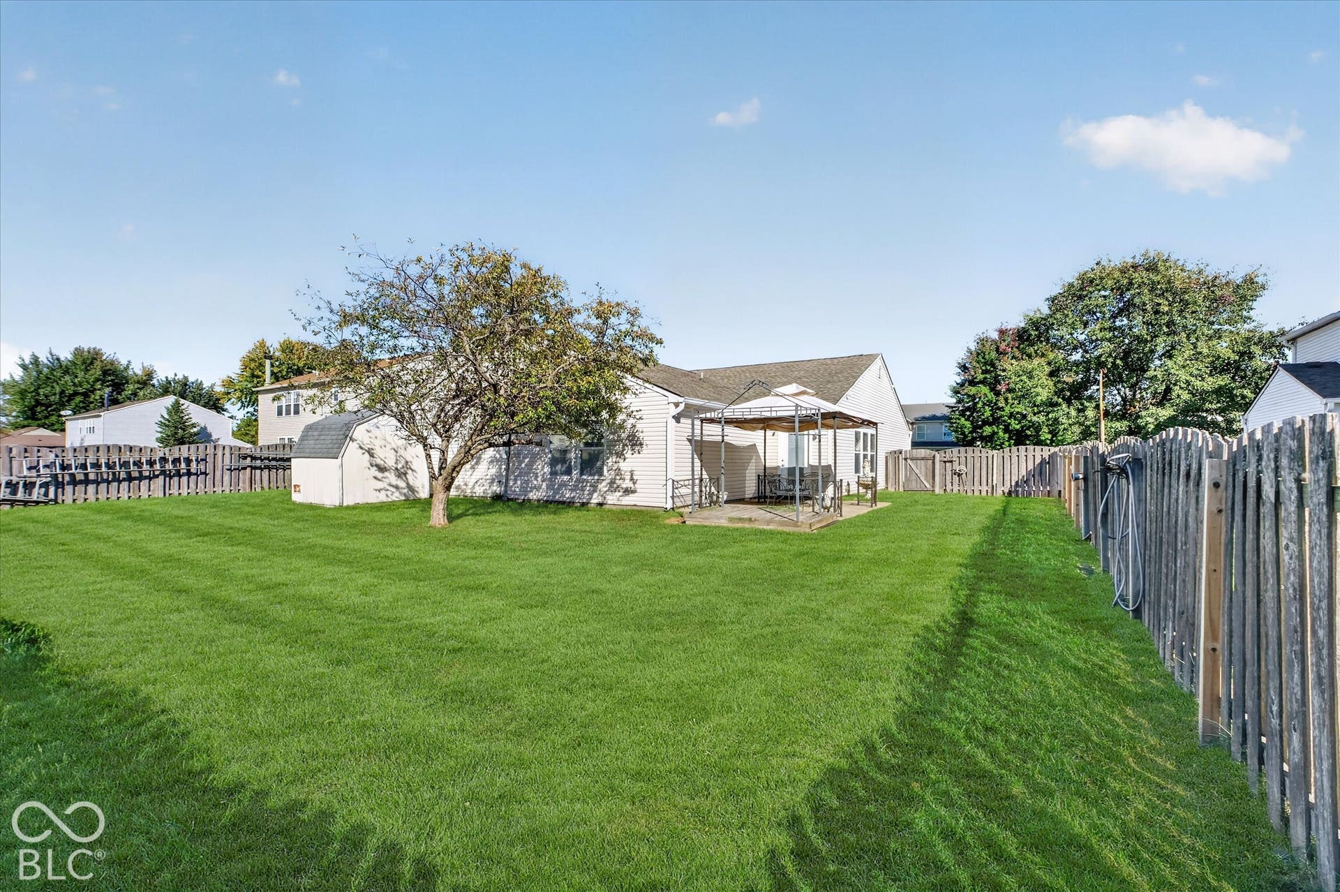 12980 Coyote Run, Fishers, IN 46038 Expansive lawn with a wooden privacy fence, mature trees, and a detached storage shed with electricity