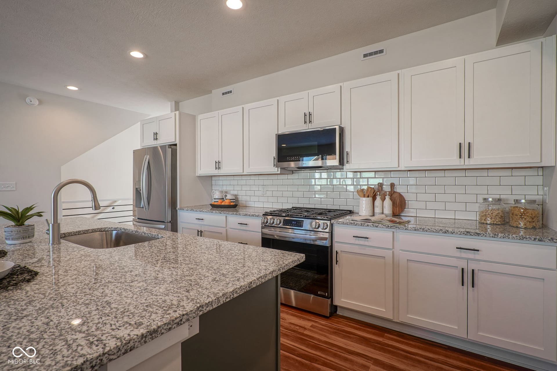 kitchen with stainless steel appliances, white cabinetry, dark wood-style flooring, light stone countertops, and recessed lighting