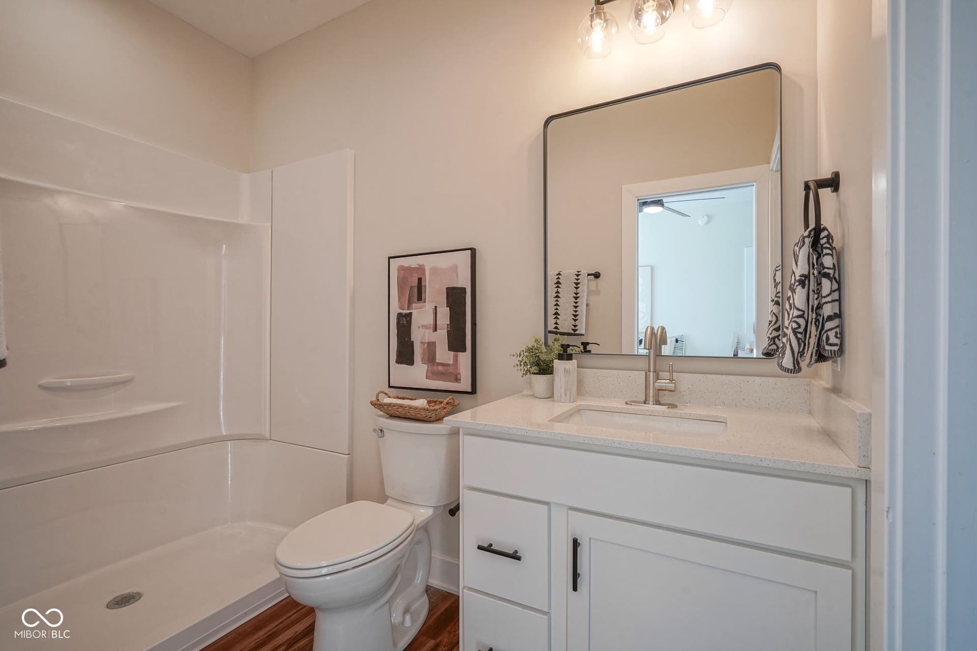 full bathroom featuring vanity, a shower, and dark wood-style floors
