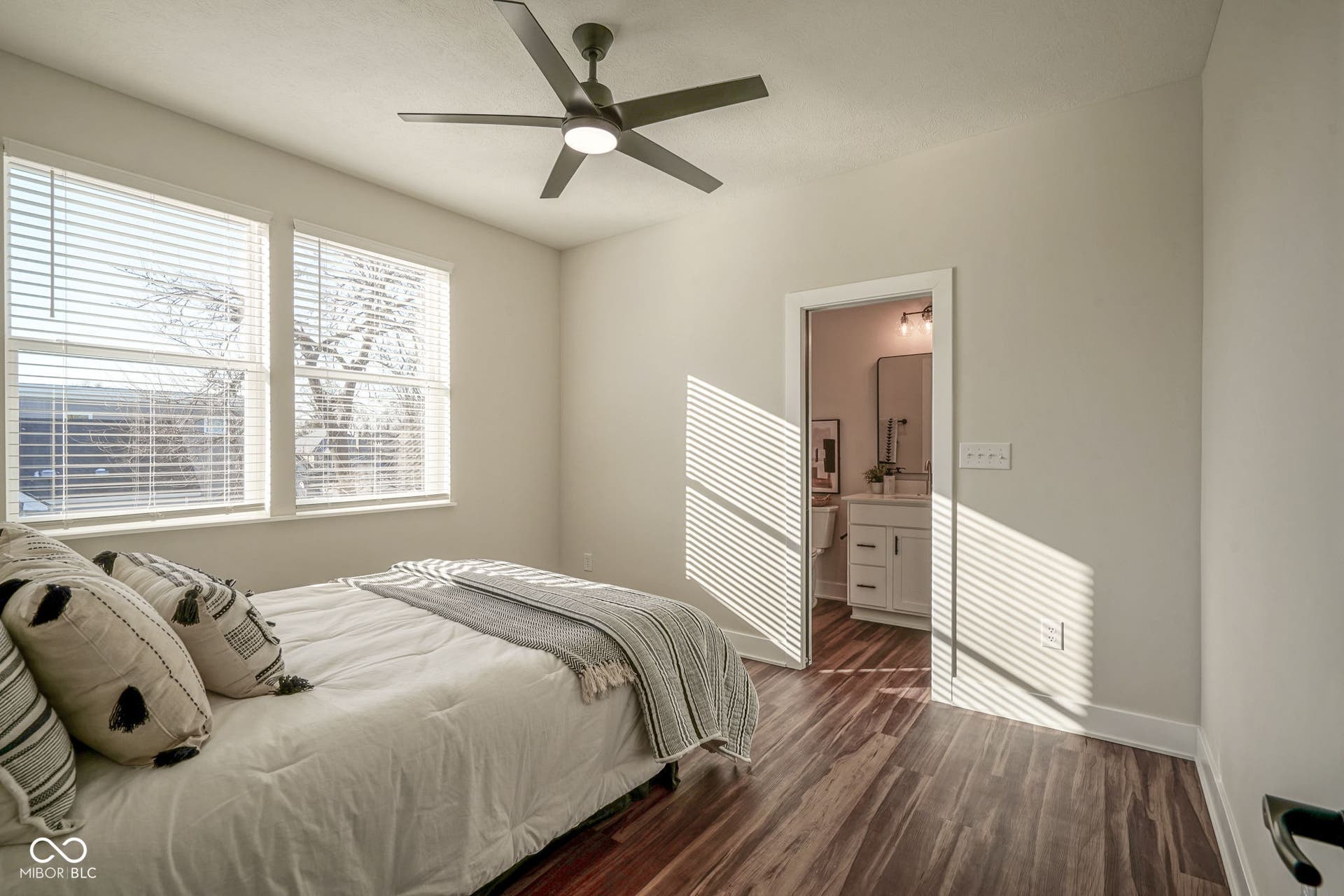 bedroom featuring dark wood-style floors, ensuite bath, and ceiling fan