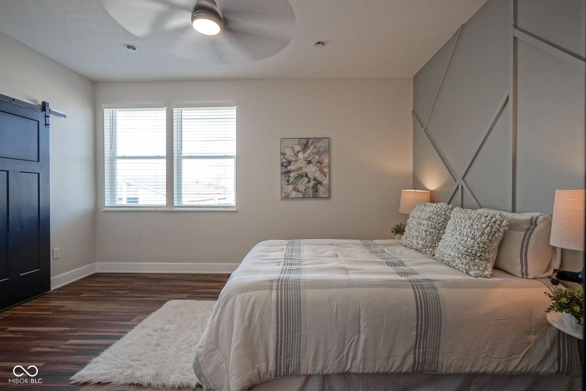 bedroom with a barn door, dark wood-type flooring, and a ceiling fan