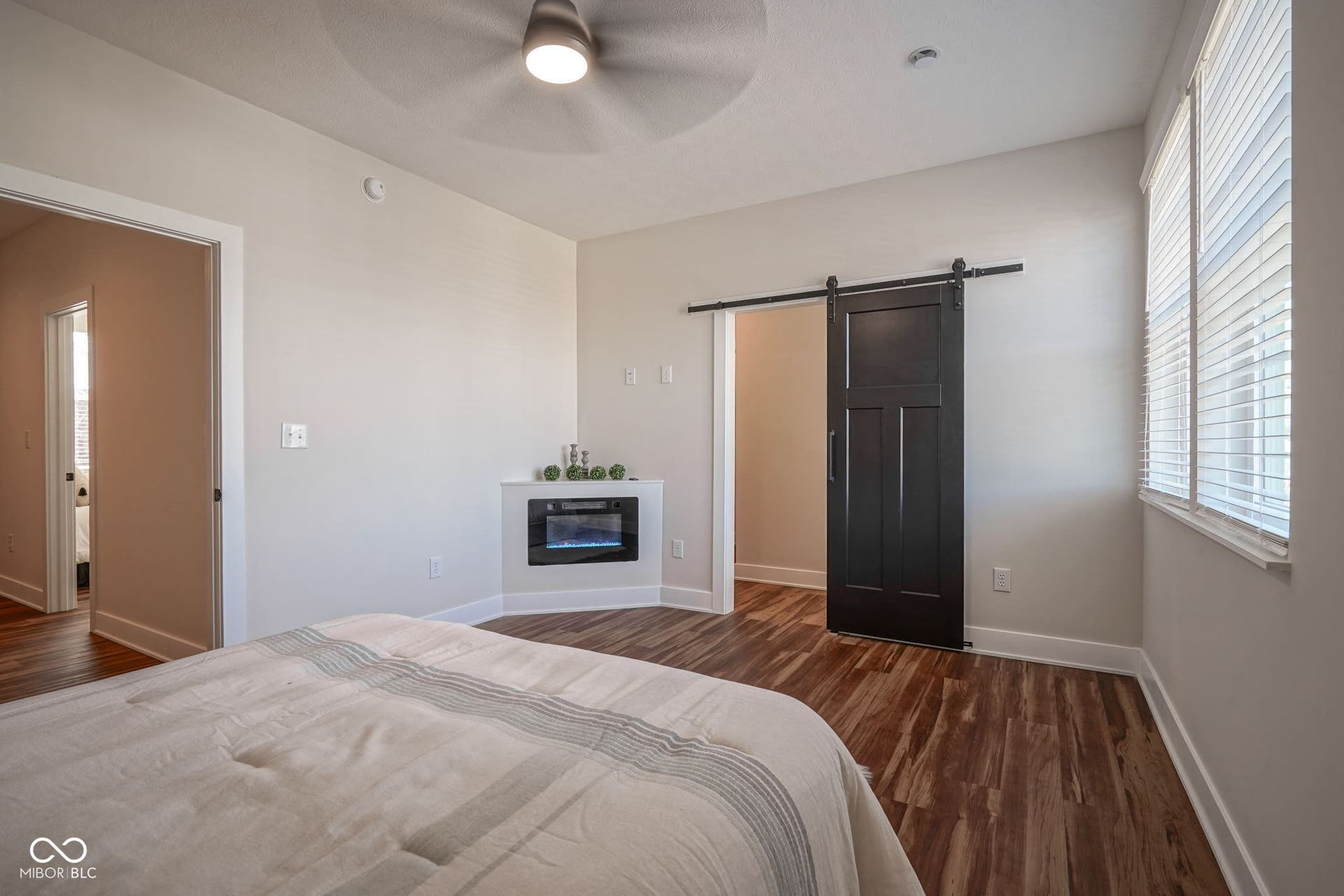 bedroom featuring a barn door, multiple windows, dark wood-style floors, and ceiling fan
