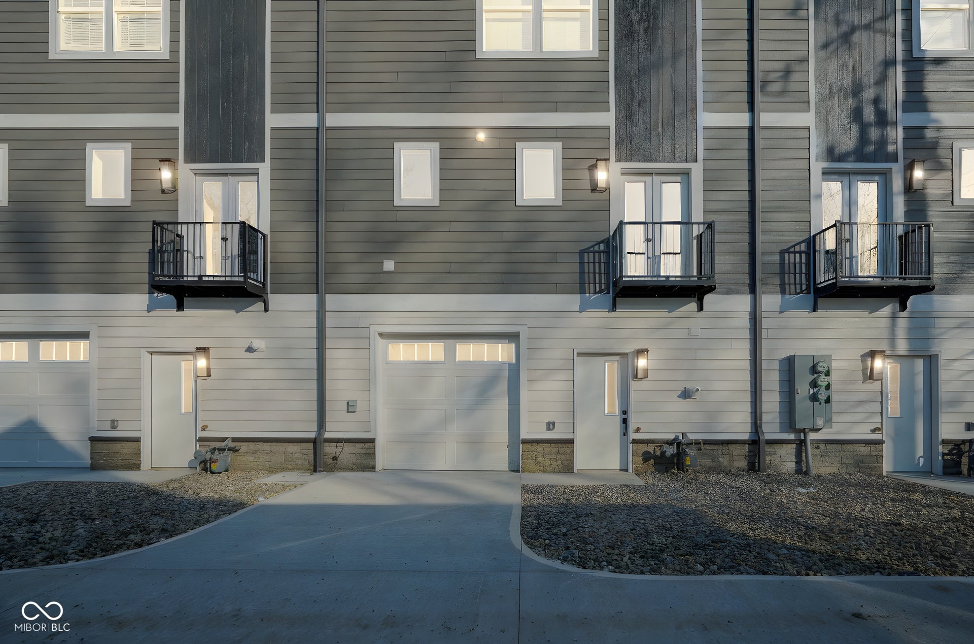 rear view of property featuring a balcony, concrete driveway, and a garage