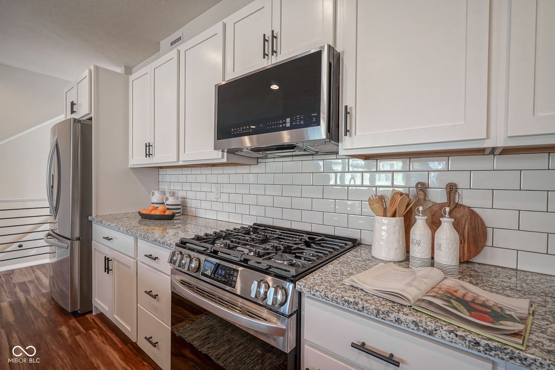 kitchen featuring stainless steel appliances, white cabinets, and light stone countertops