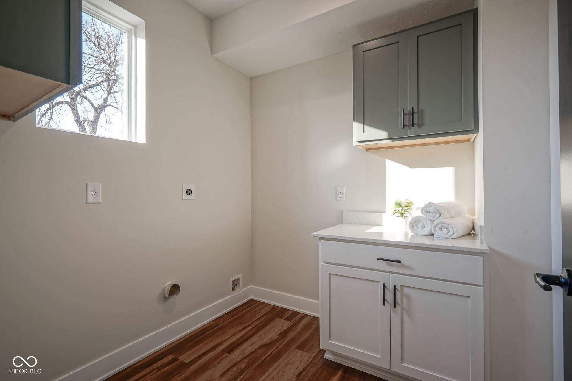 washroom featuring electric dryer hookup, dark wood-style floors, and cabinet space