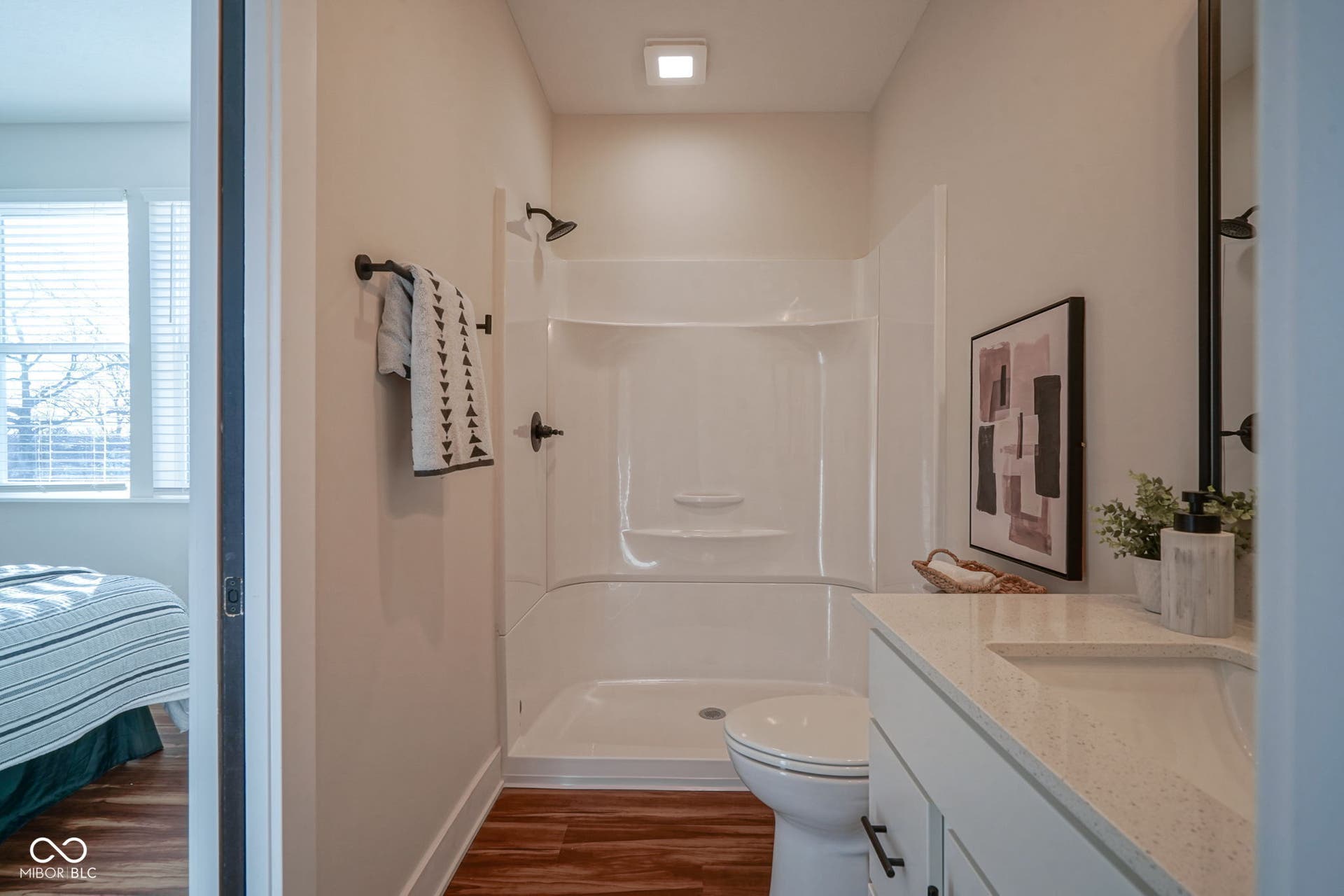 ensuite bathroom with a shower stall, dark wood-style floors, and vanity