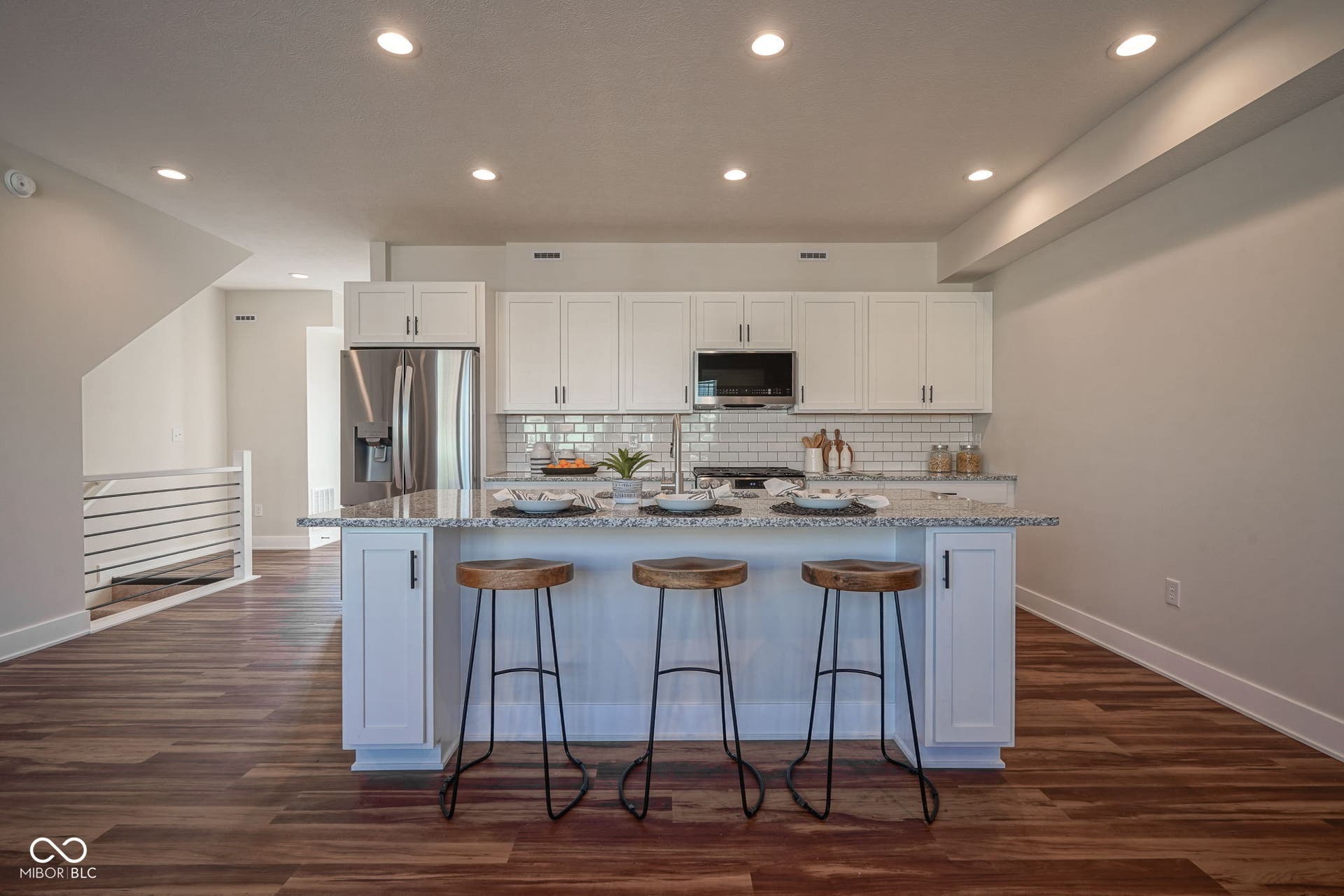 kitchen featuring white cabinetry, light stone countertops, dark wood-type flooring, a center island with sink, and appliances with stainless steel finishes