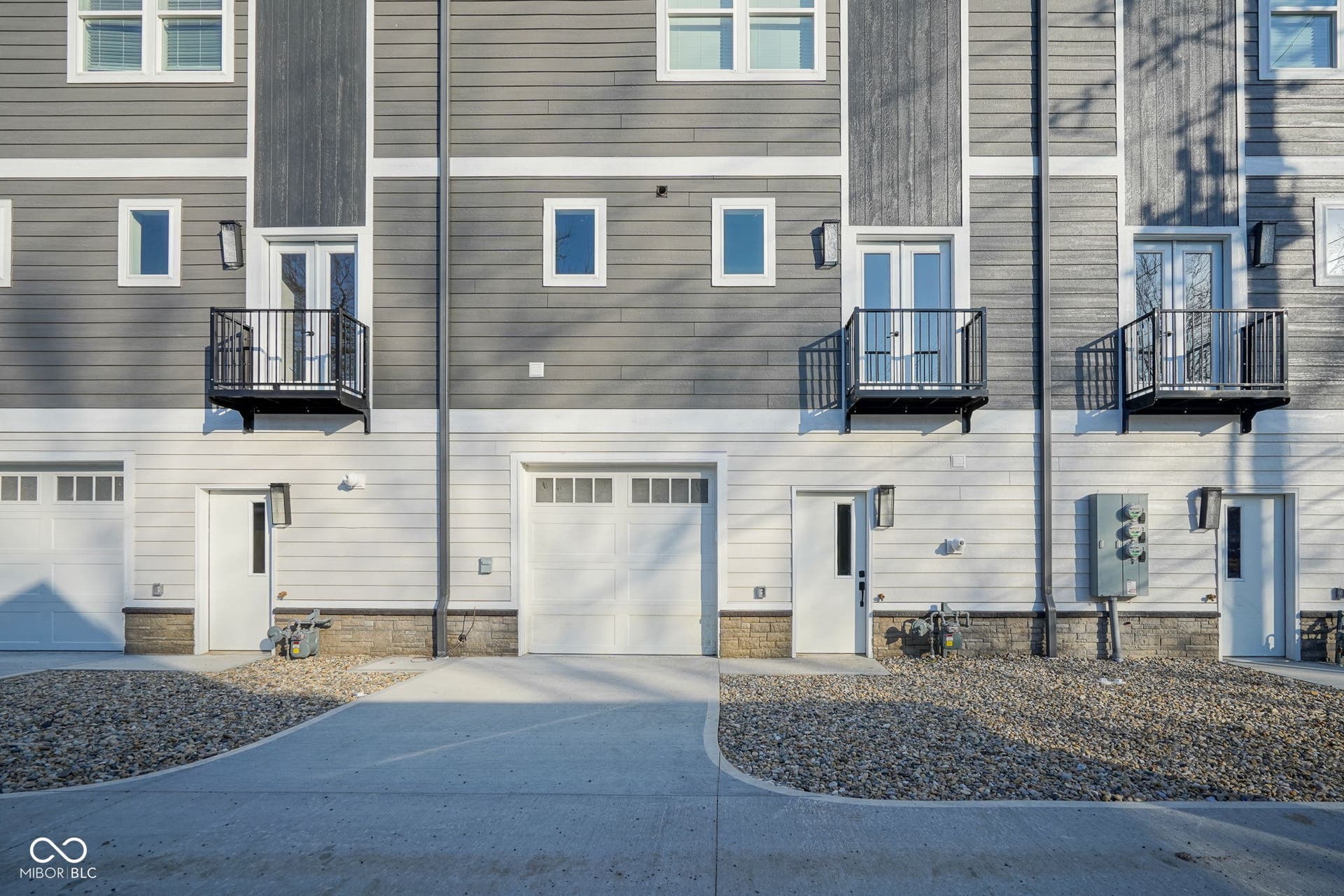 view of side of property featuring a balcony, concrete driveway, and a garage