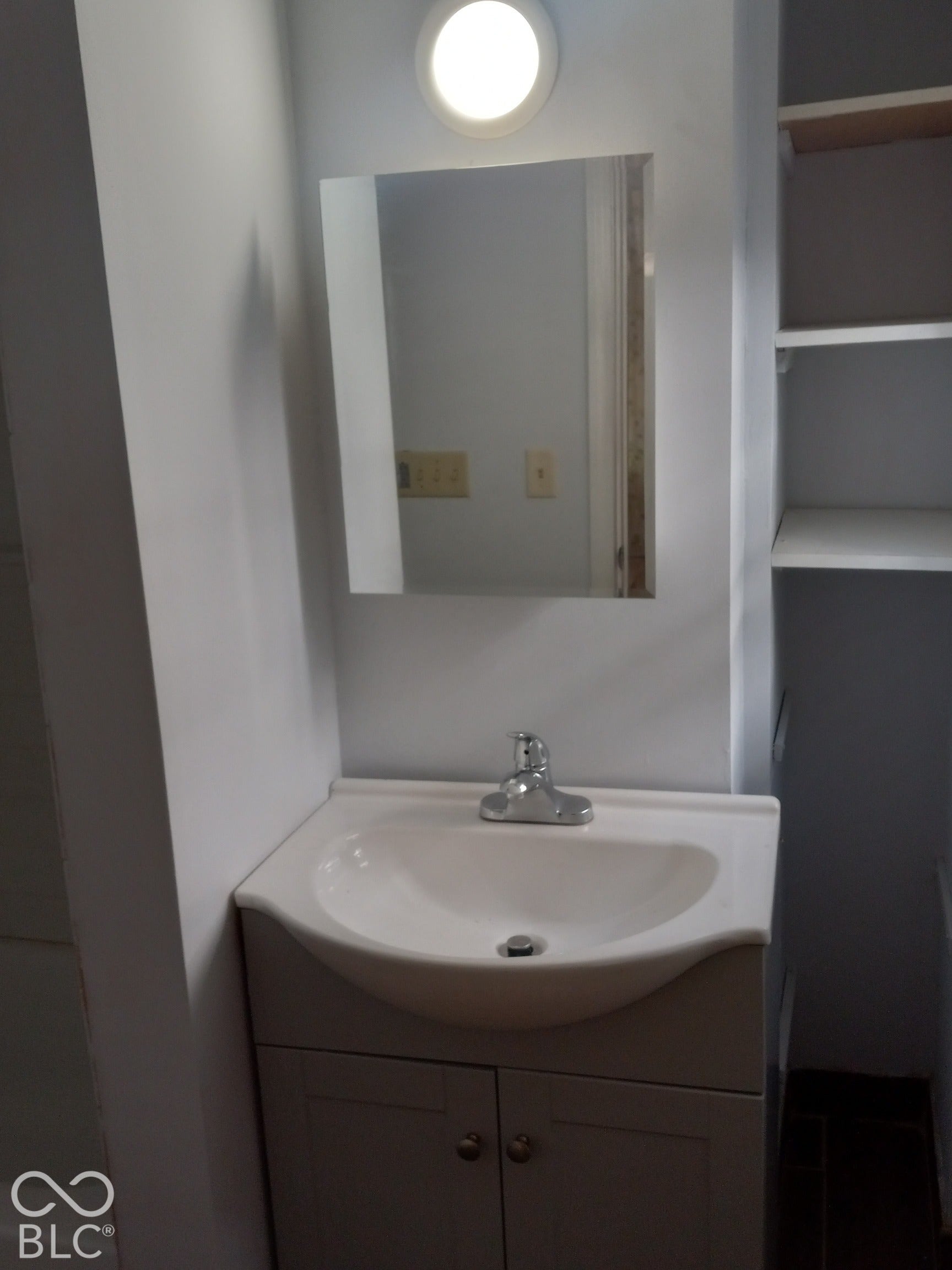 Vanity with an integrated white sink, chrome faucet, and storage cabinetry