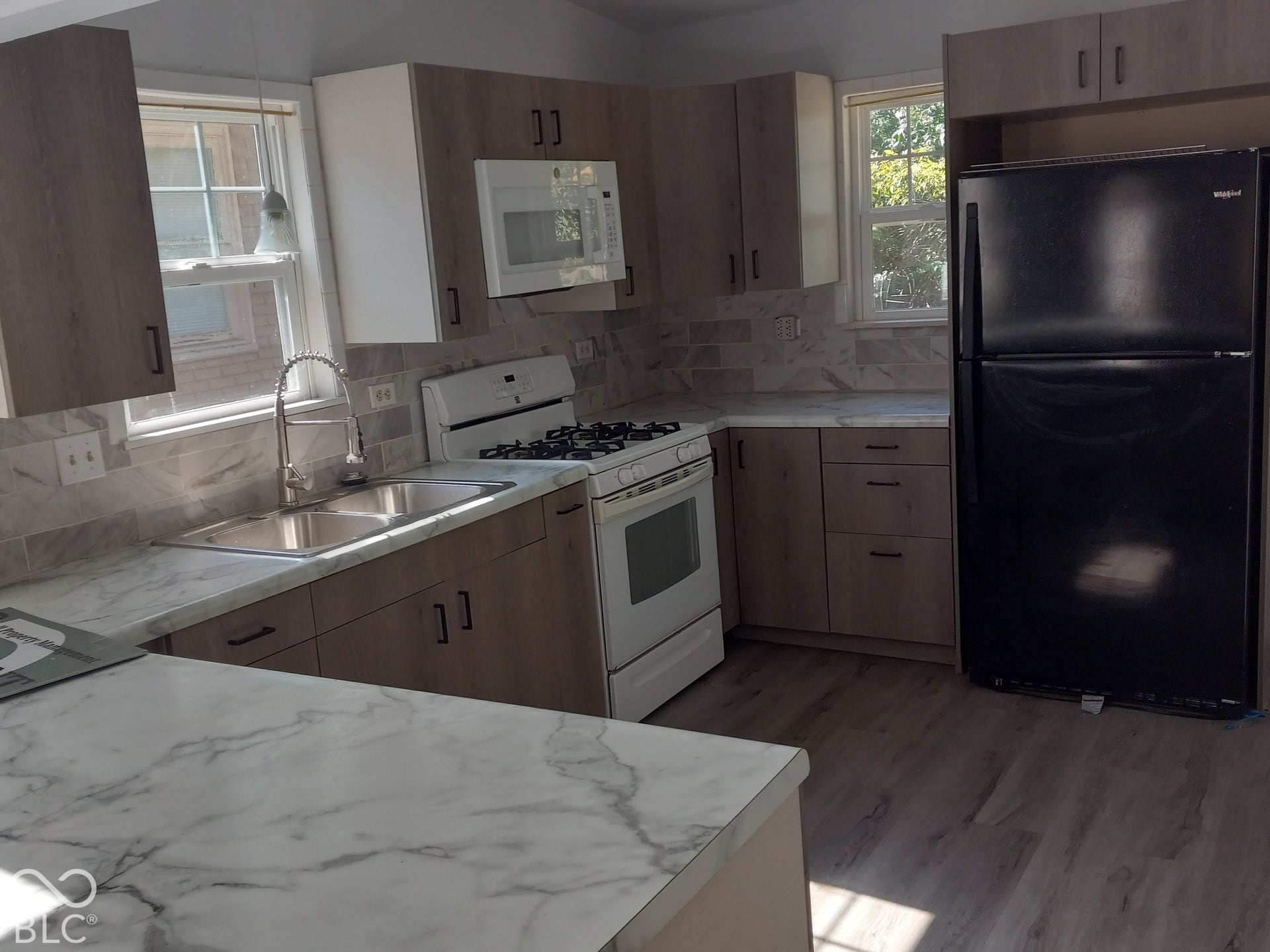 Kitchen featuring wood-look cabinetry, white countertops, tile backsplash, and wood-finish flooring
