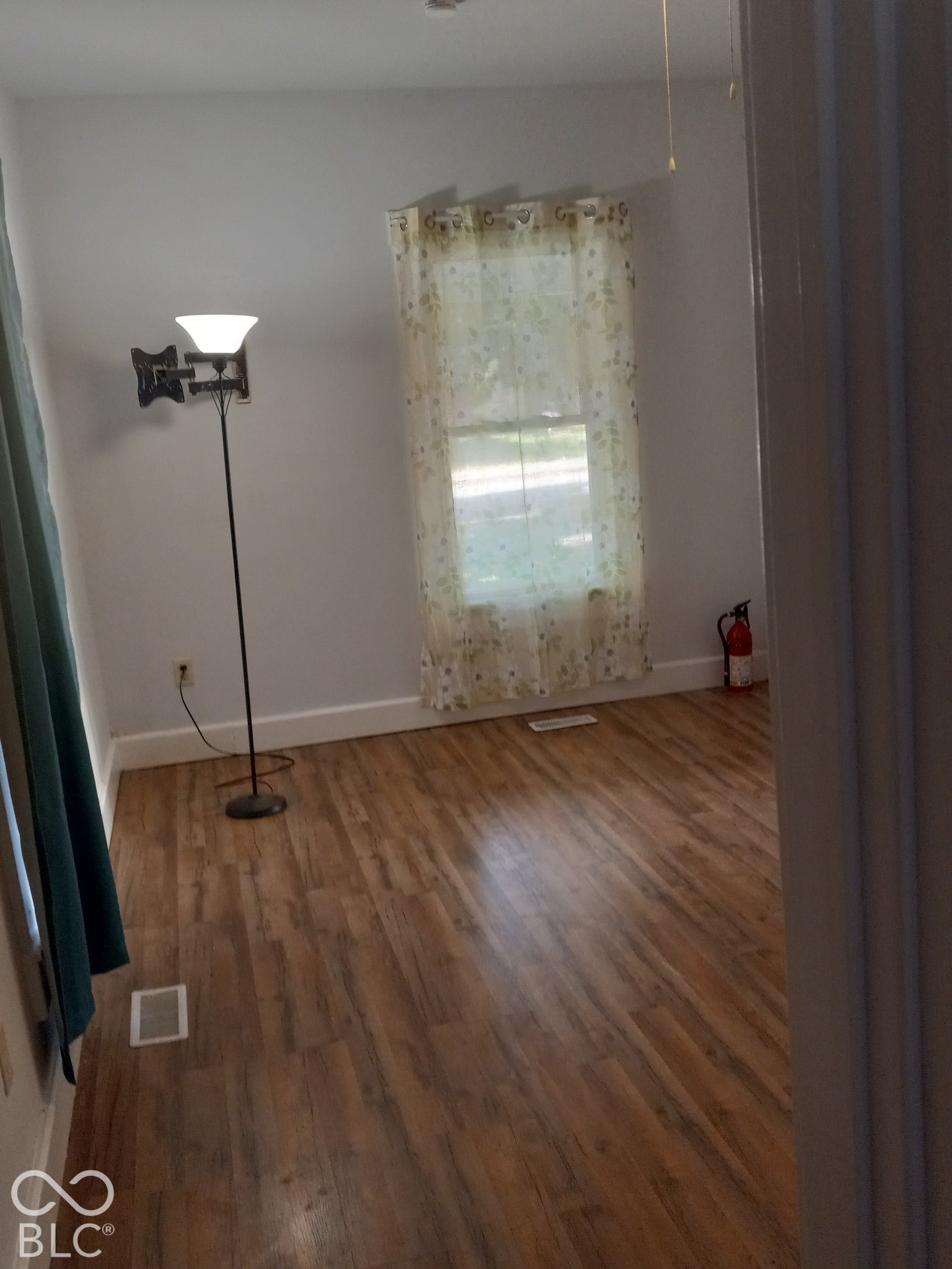 Wood-finish flooring with white trim and a window with natural light