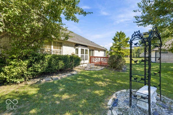 Brick exterior with a gabled roof, rear deck with wood railing, and established landscaping